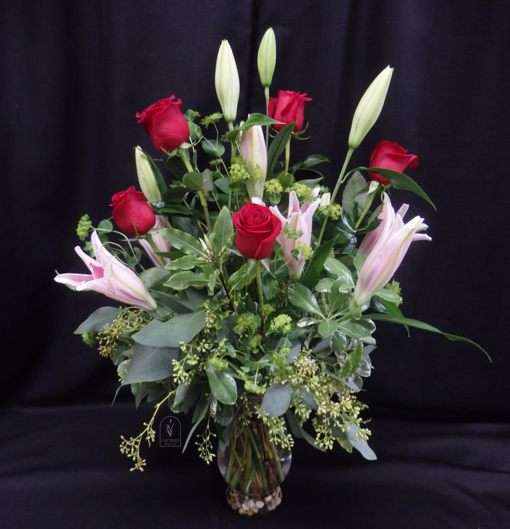 Bouquet of red roses and pink lilies in a glass vase