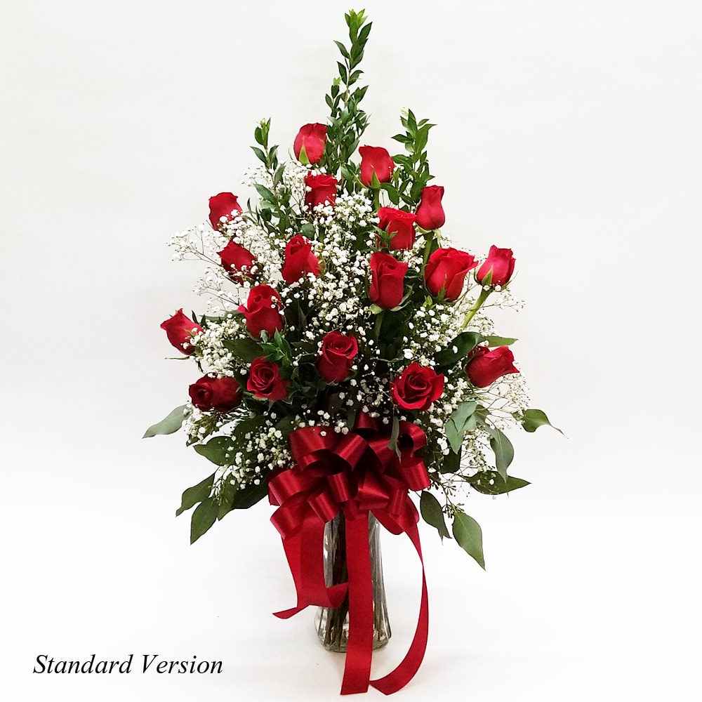 Red roses arranged in a clear glass vase with a red ribbon