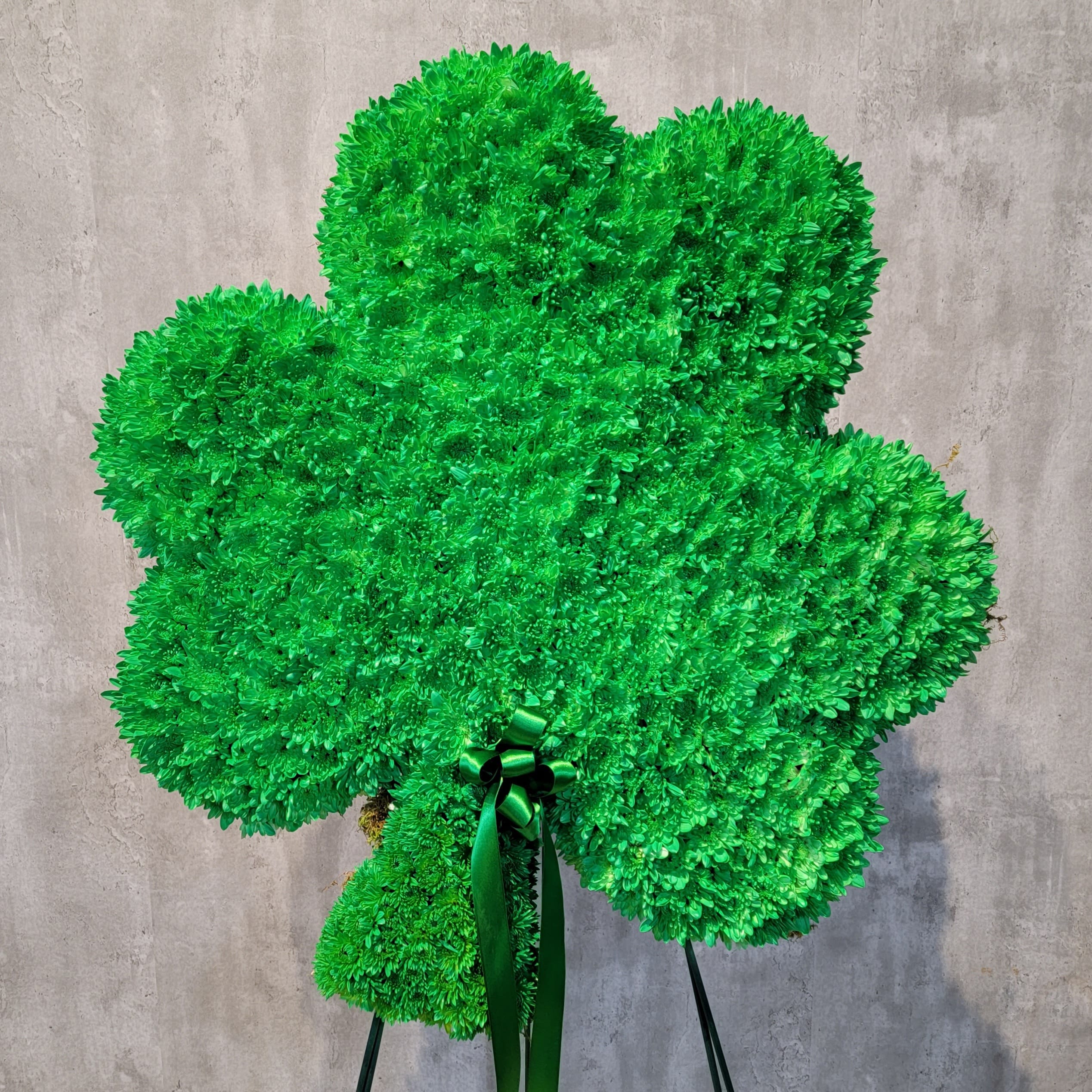 Green shamrock-shaped floral arrangement with a ribbon bow