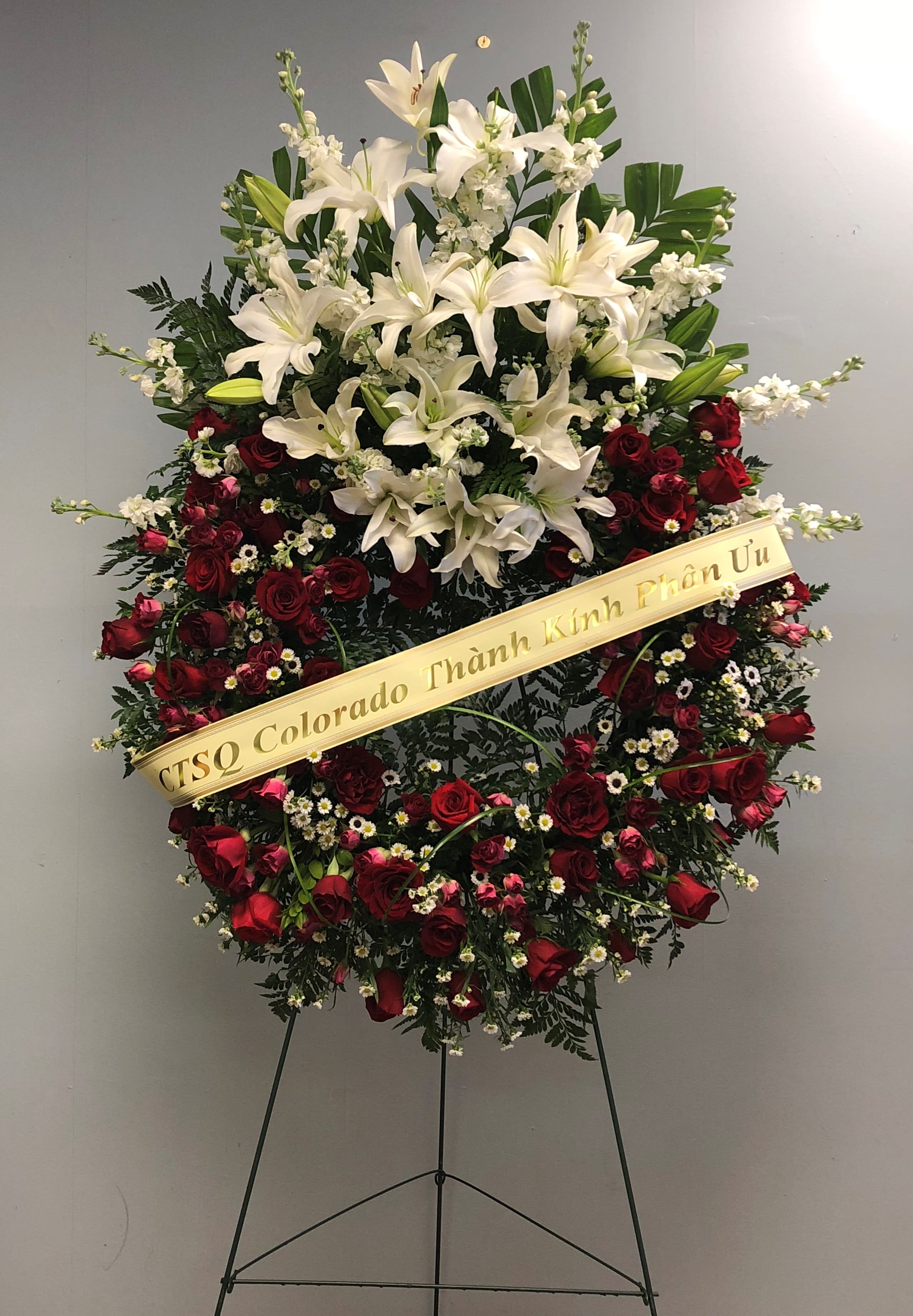 Standing floral wreath with white lilies and red roses on an easel