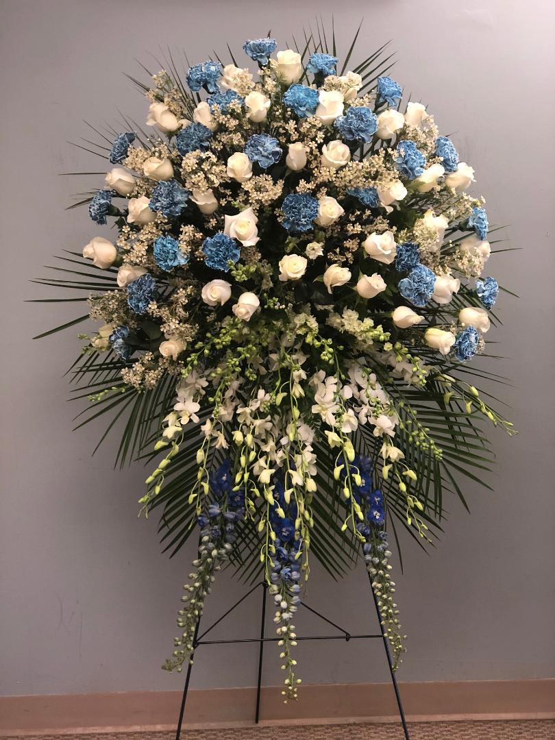 Large standing floral spray with white roses, blue carnations, and orchids