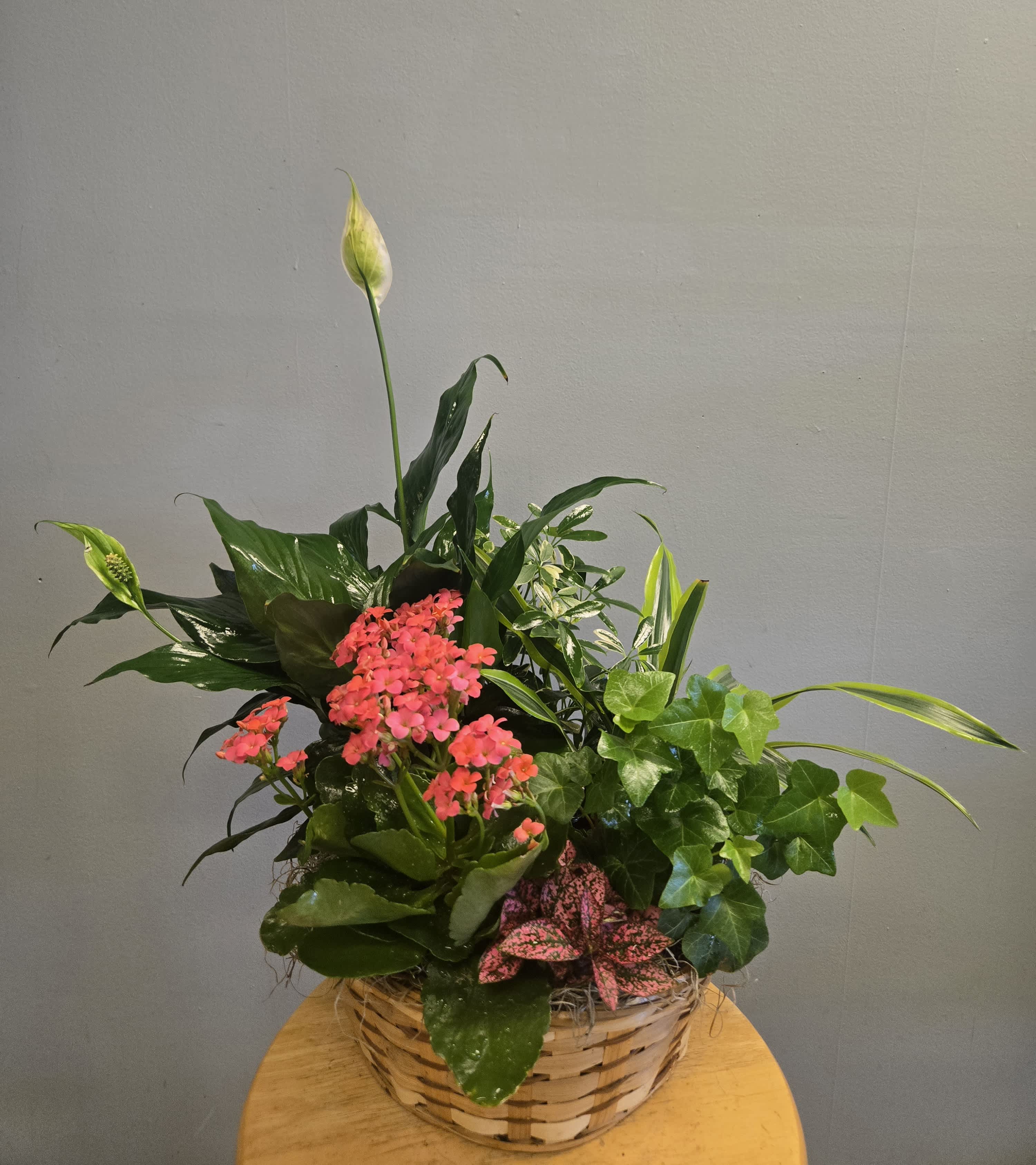 Basket arrangement with pink flowers and white peace lilies