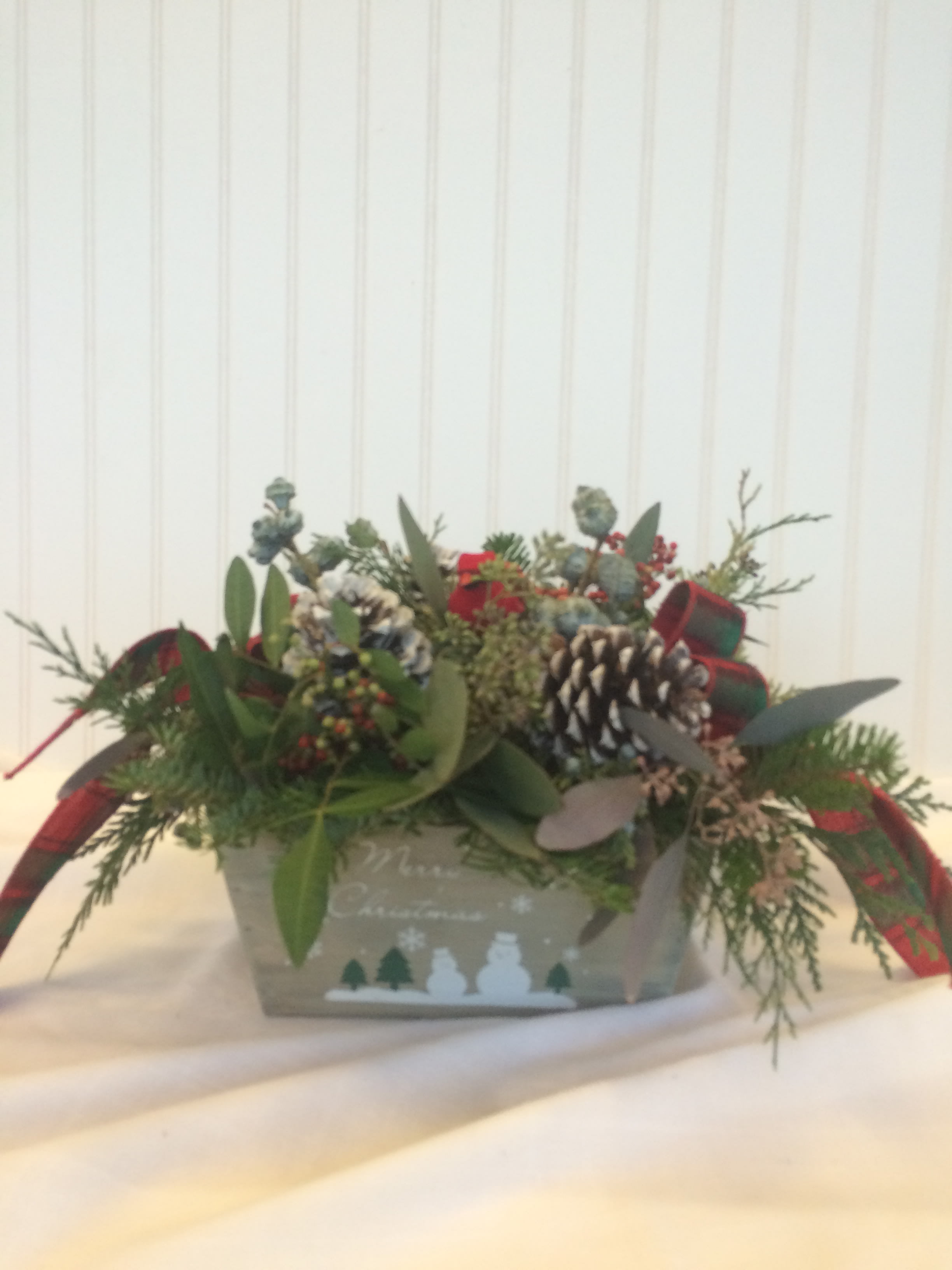 Holiday arrangement in a decorative box with pinecones and ribbon