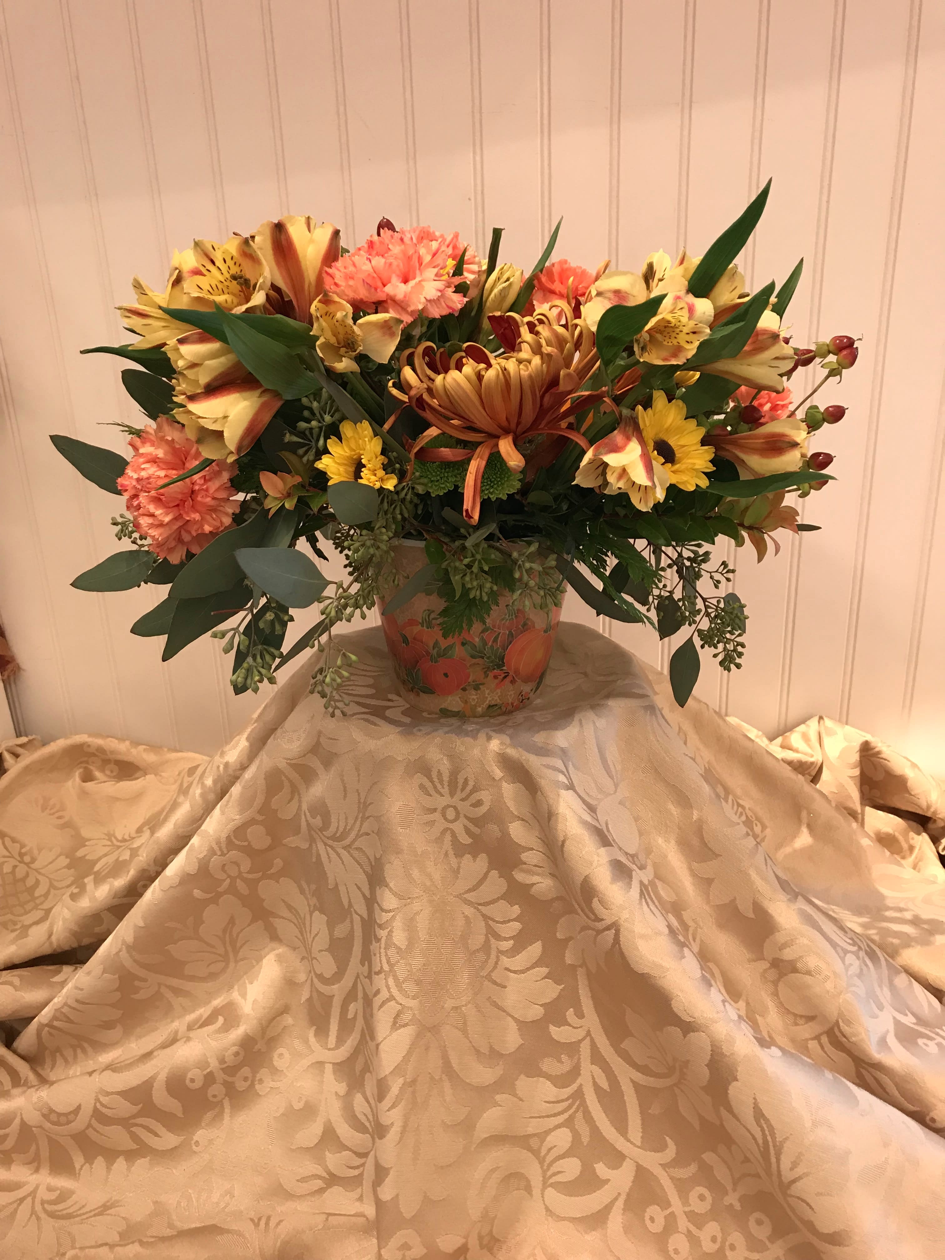 Mixed bouquet in a decorative vase with yellow, coral, and burgundy flowers