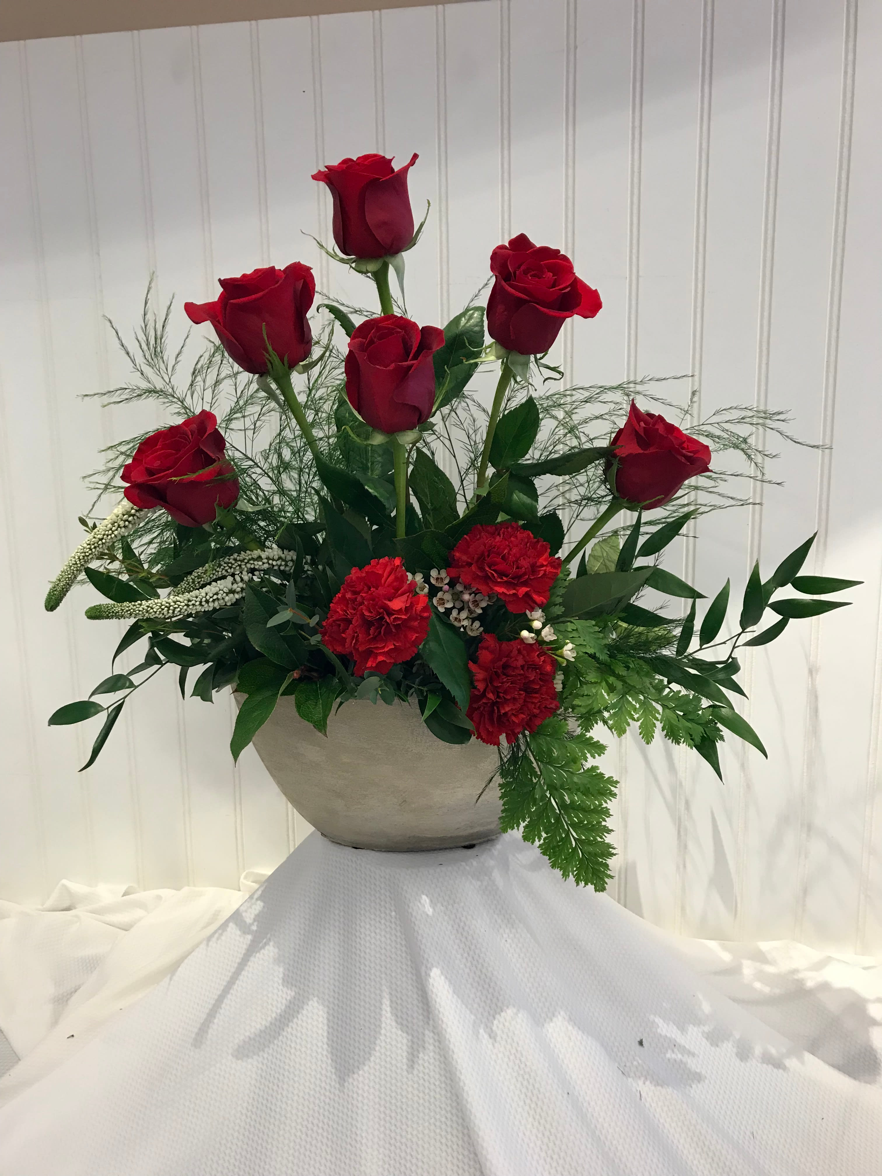 Red roses and carnations arranged in a gray bowl vase