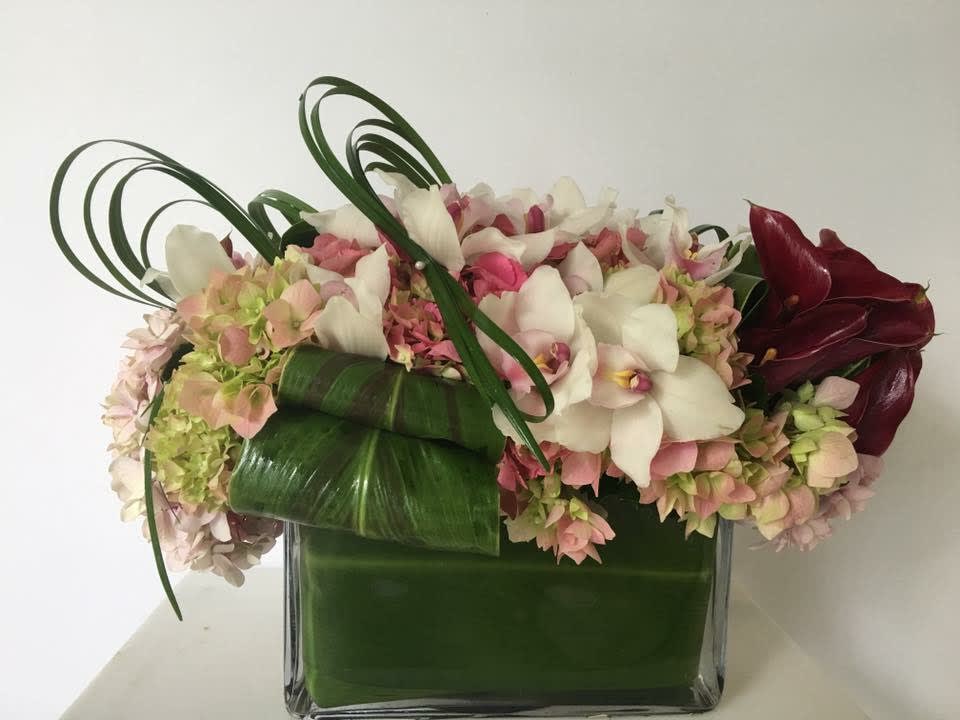 Pink and white floral arrangement in a square glass vase