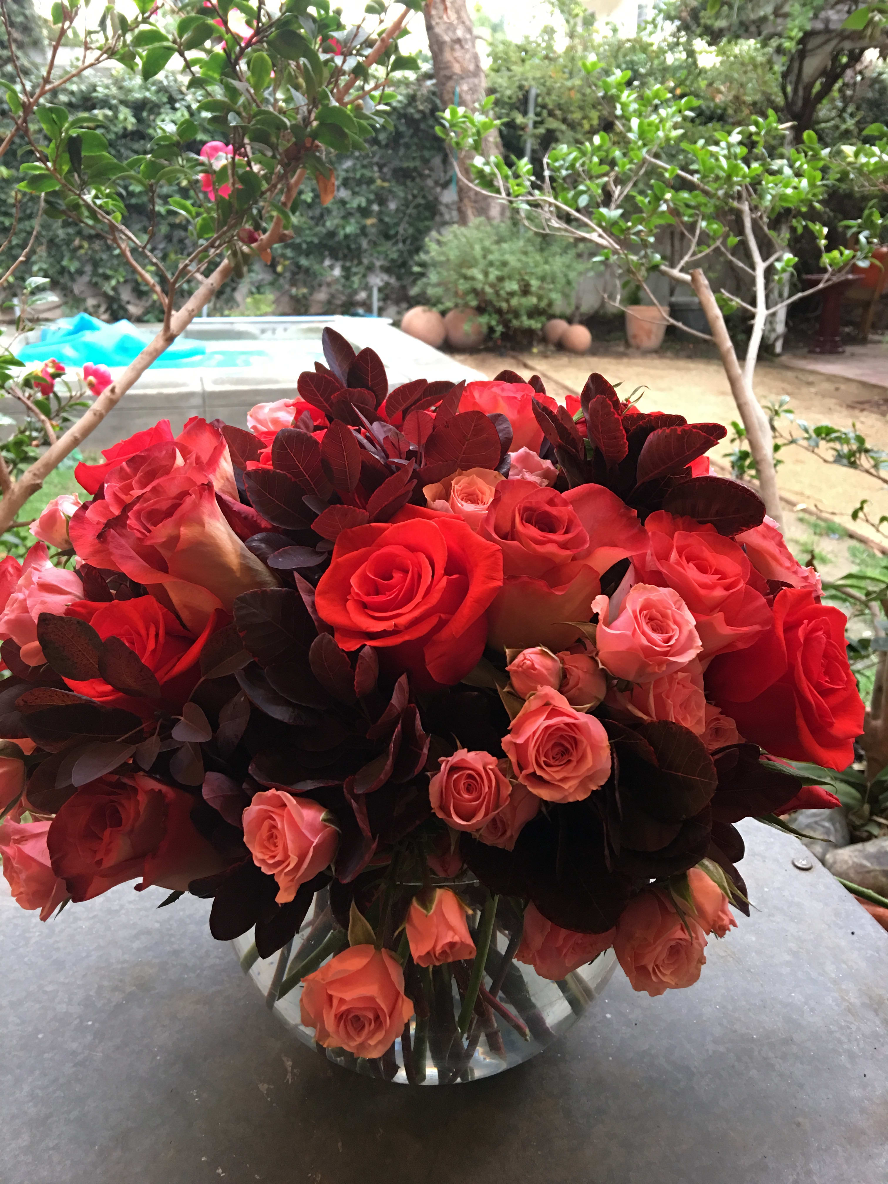 Red and pink roses arranged in a clear glass vase