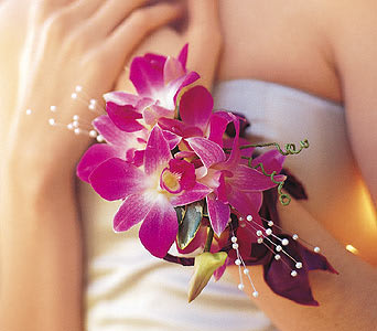 Pink orchid corsage with pearl accents on a wrist