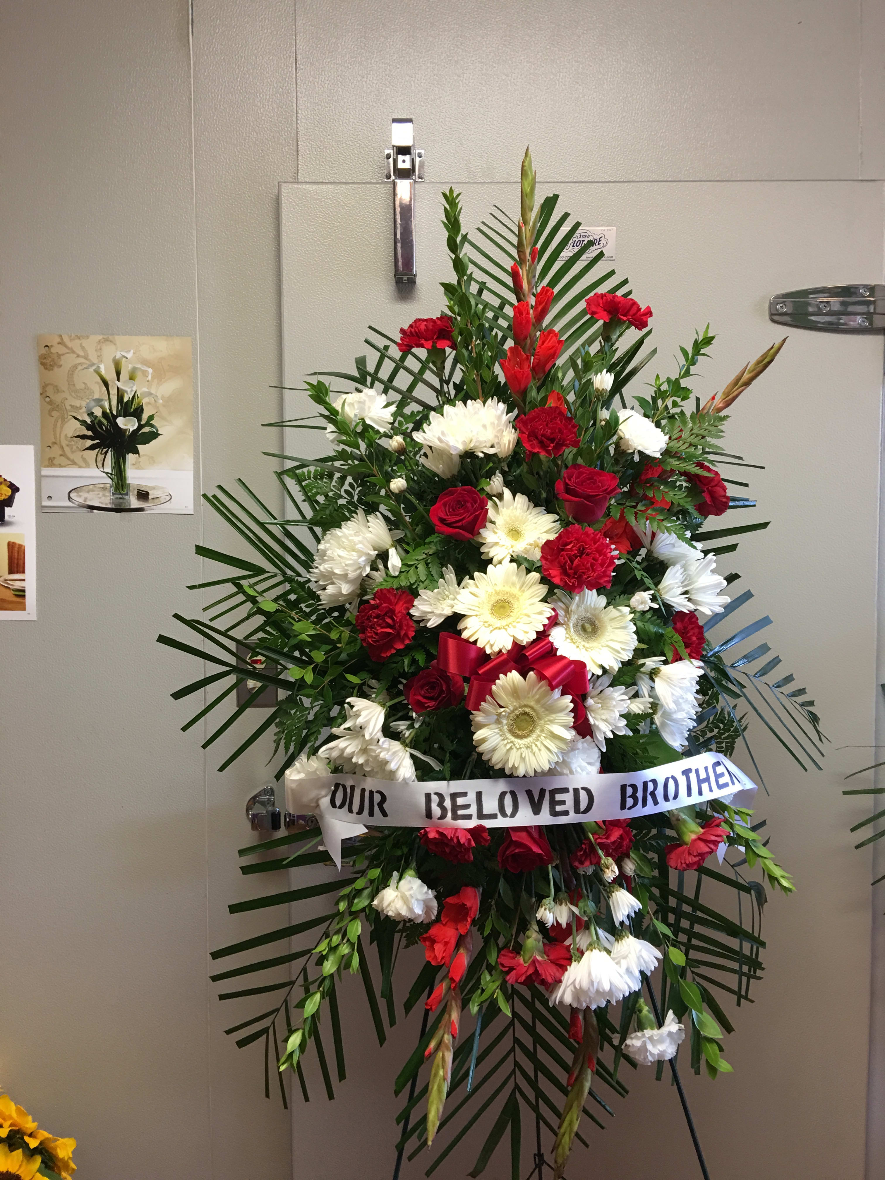 Standing red and white funeral spray with ribbon tribute