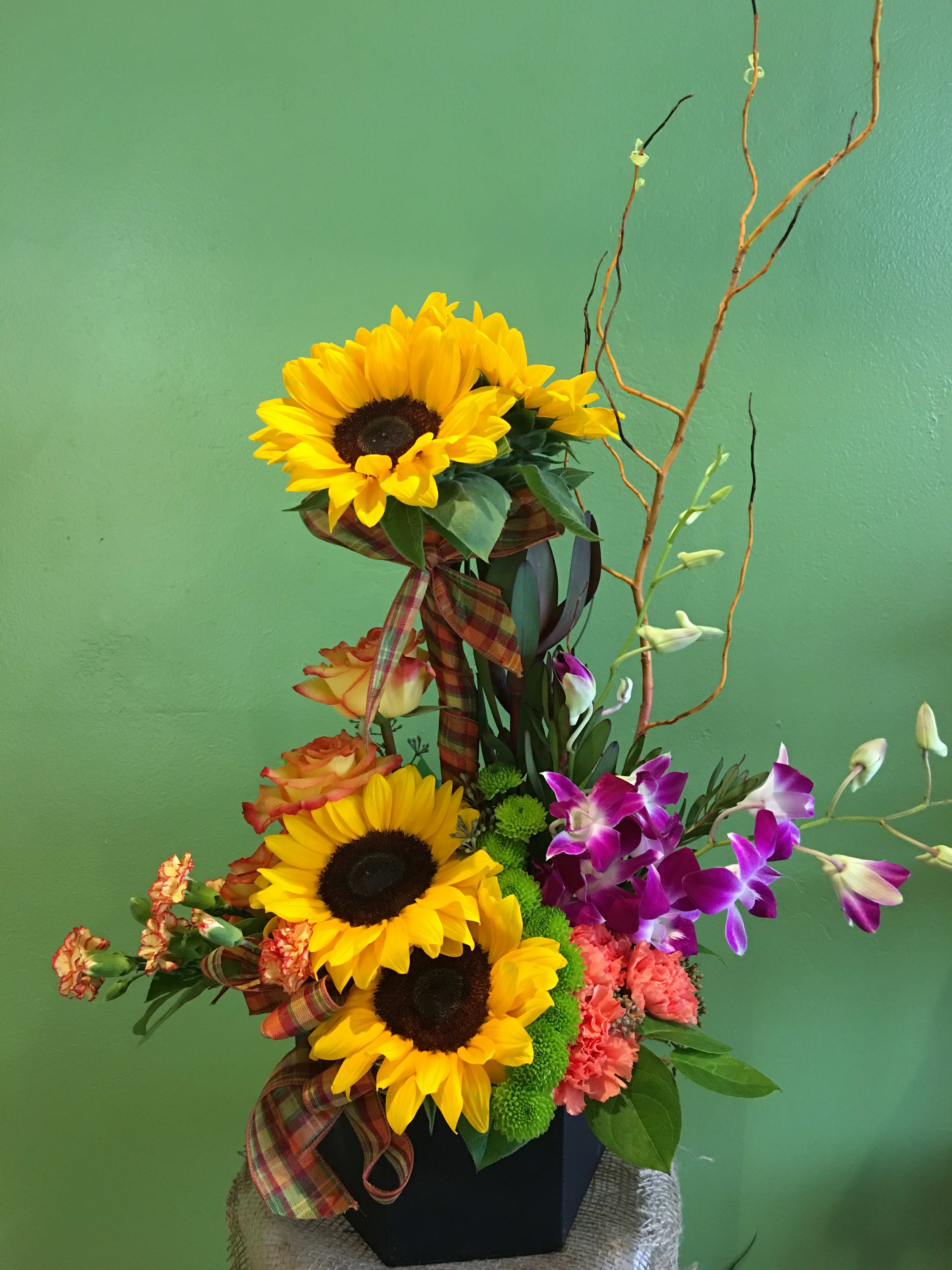 Tall mixed bouquet with sunflowers, orchids, and roses in a black container