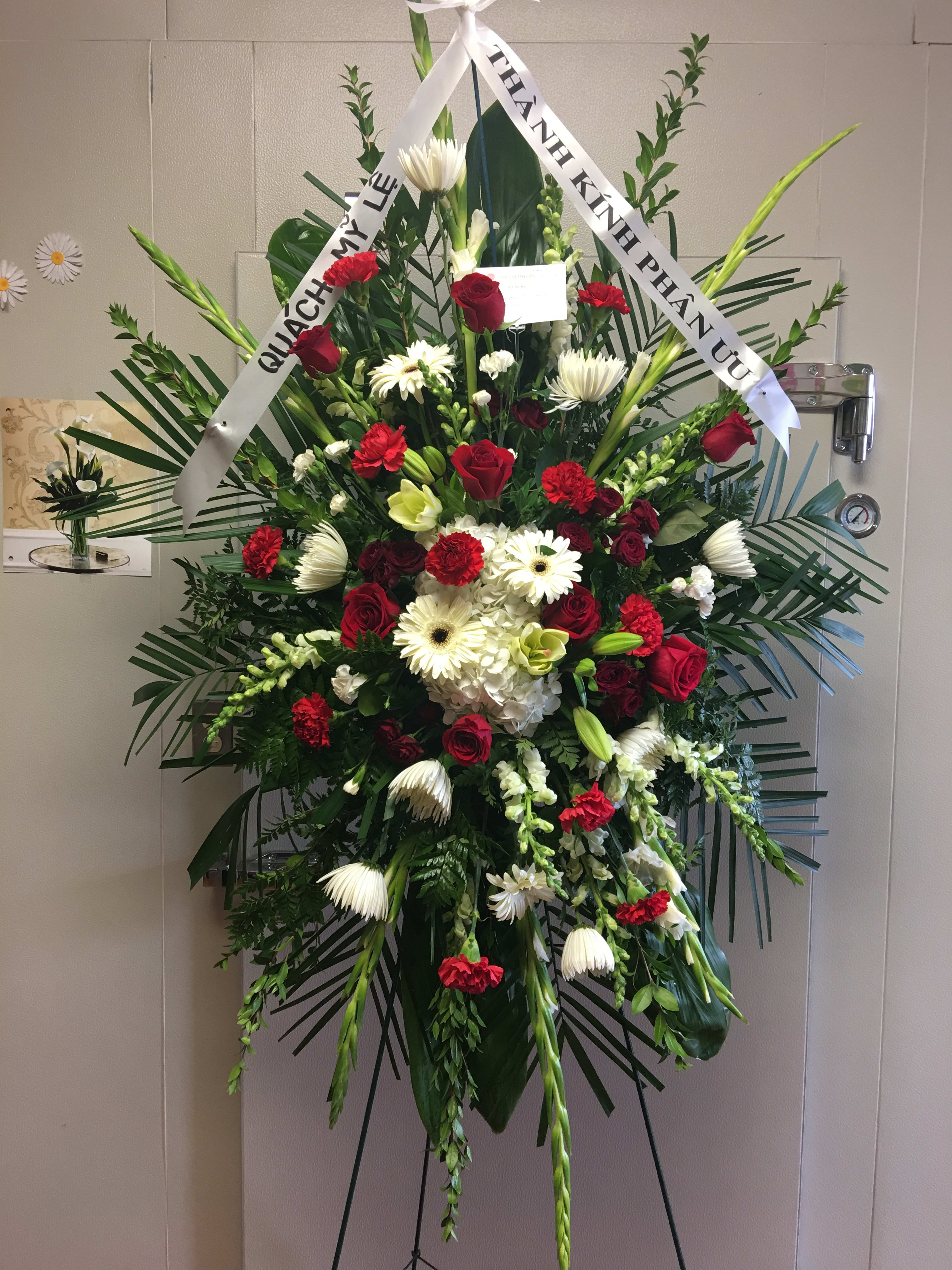 Standing funeral spray with red and white flowers on an easel