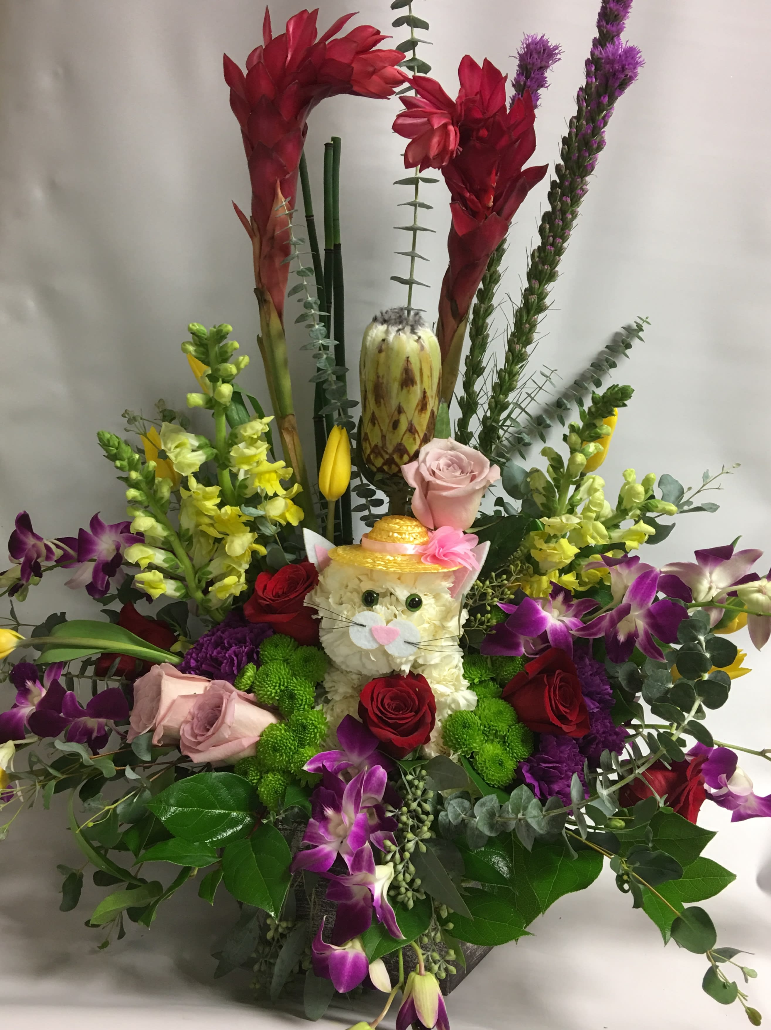 Colorful floral arrangement with a cat face centerpiece and orchids