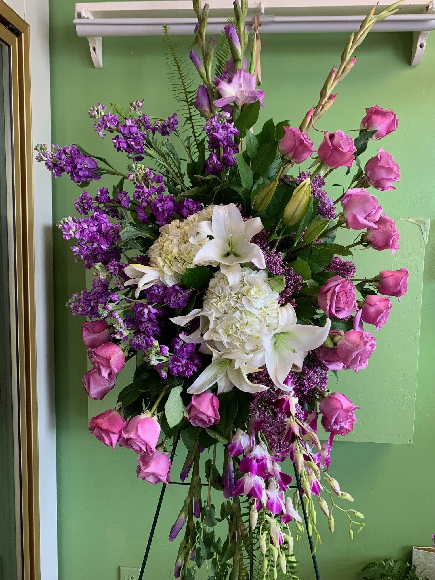 Standing floral spray with pink roses, white lilies, and purple blooms
