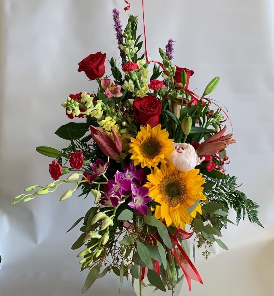 Mixed bouquet with red roses, sunflowers, lilies, and orchids