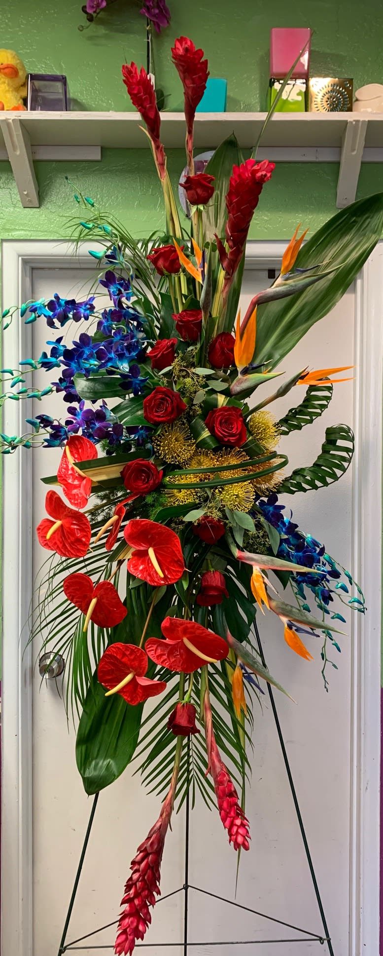 Tall tropical floral arrangement with red roses, blue orchids, and orange bird-of-paradise