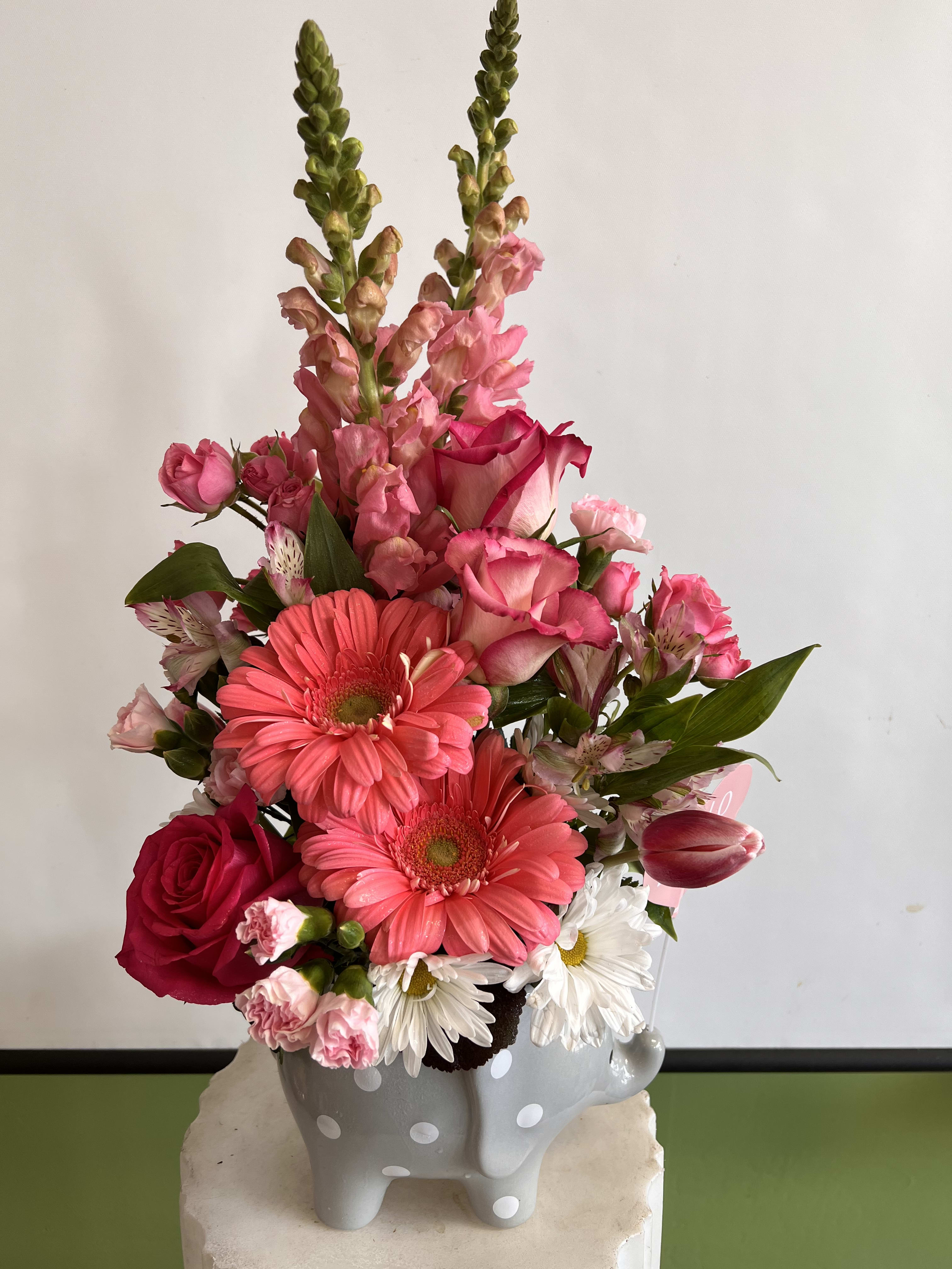 Pink and white mixed flower arrangement in a gray polka-dot vase