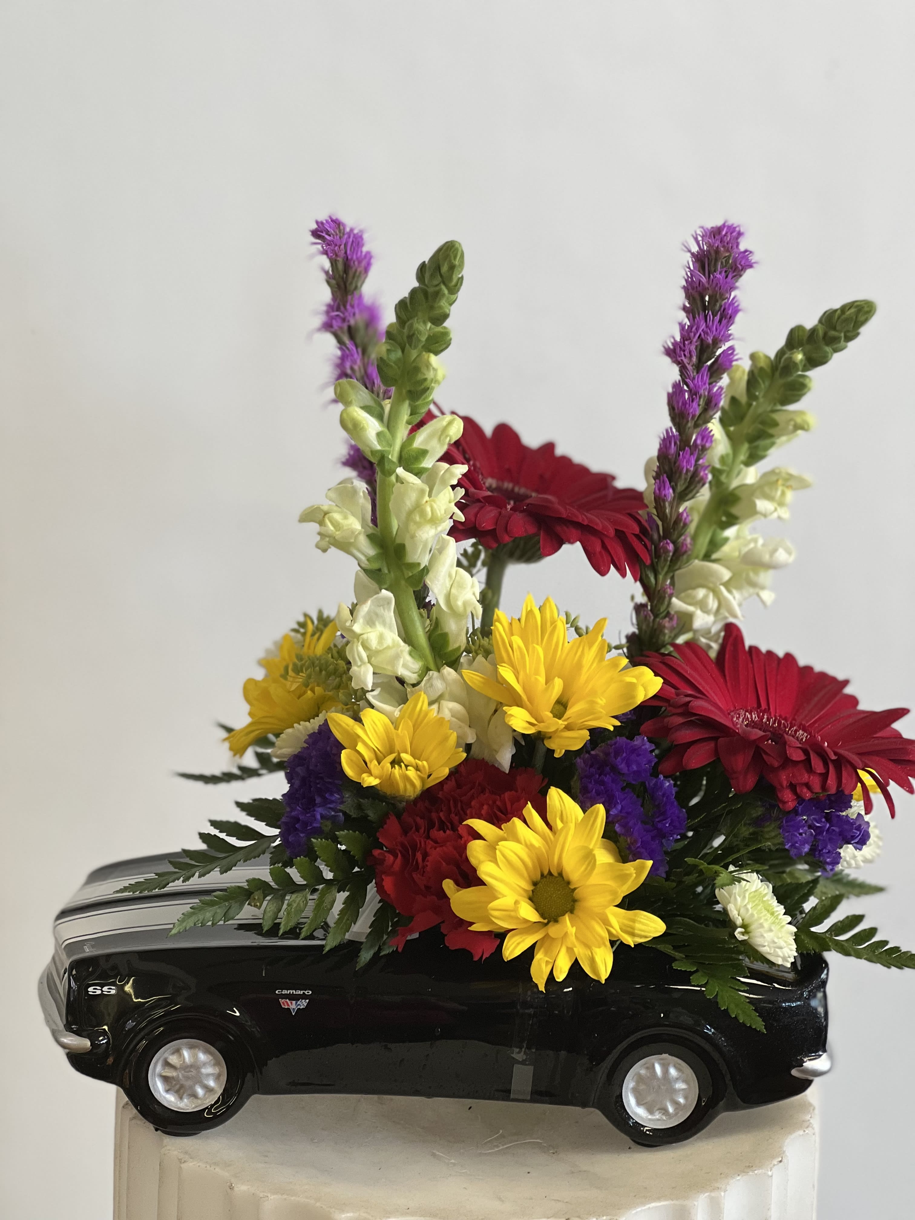 Colorful flower arrangement in a black toy car container