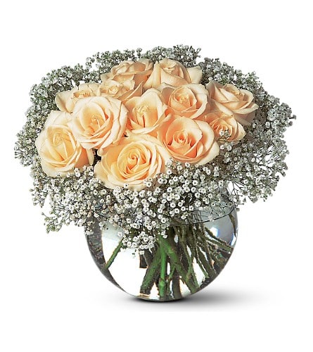 Peach roses in a round glass vase with baby's breath