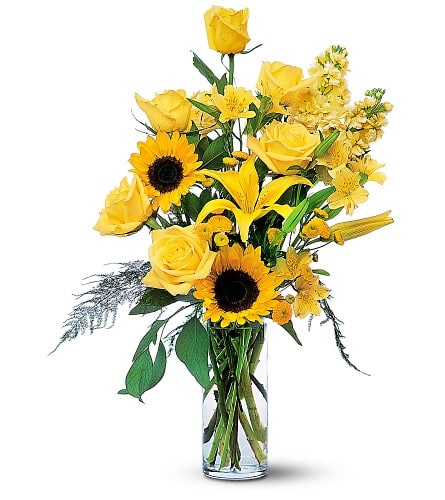Yellow roses and sunflowers arranged in a clear glass vase