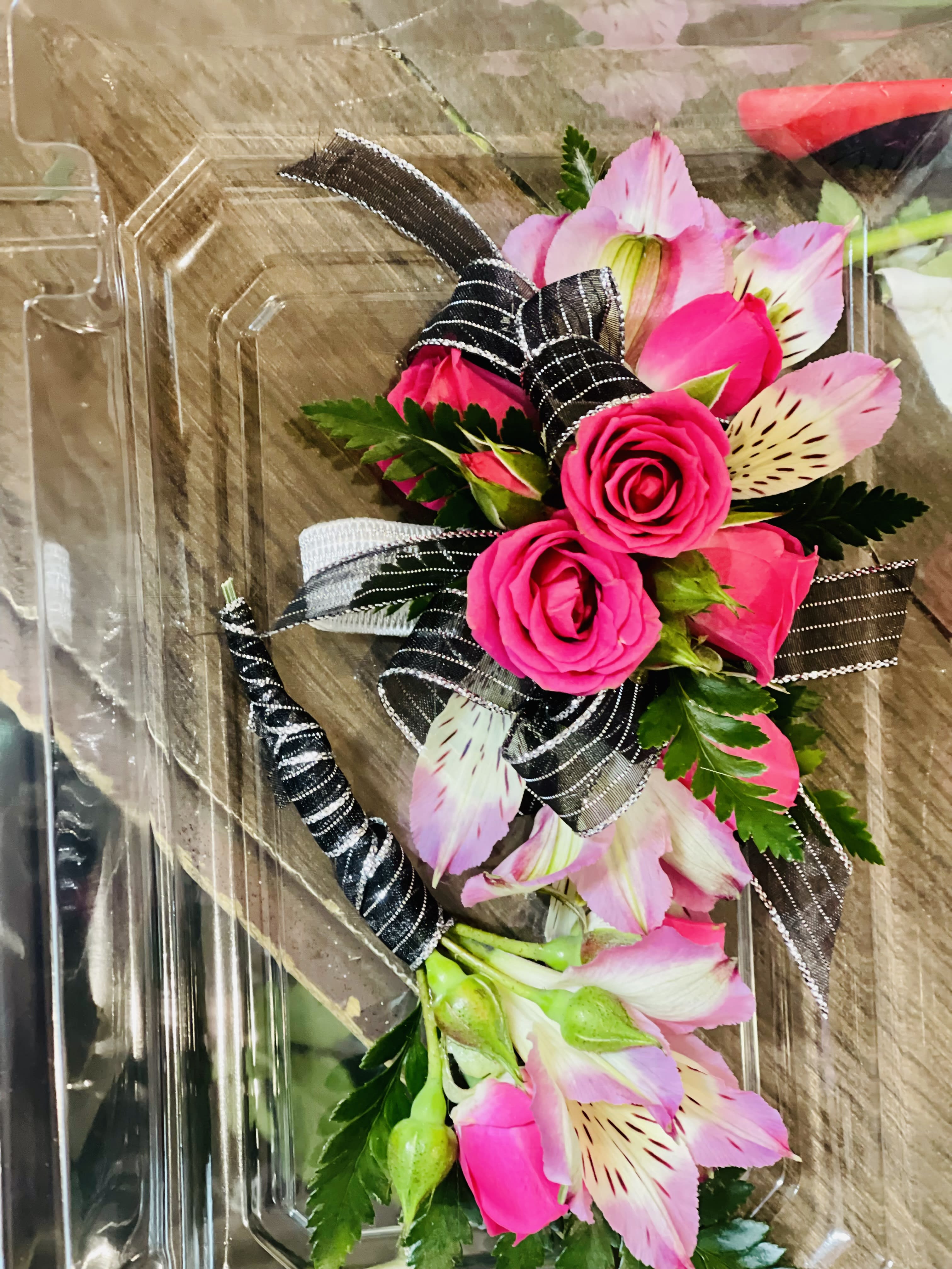Pink roses and alstroemeria in a clear plastic box with black ribbon
