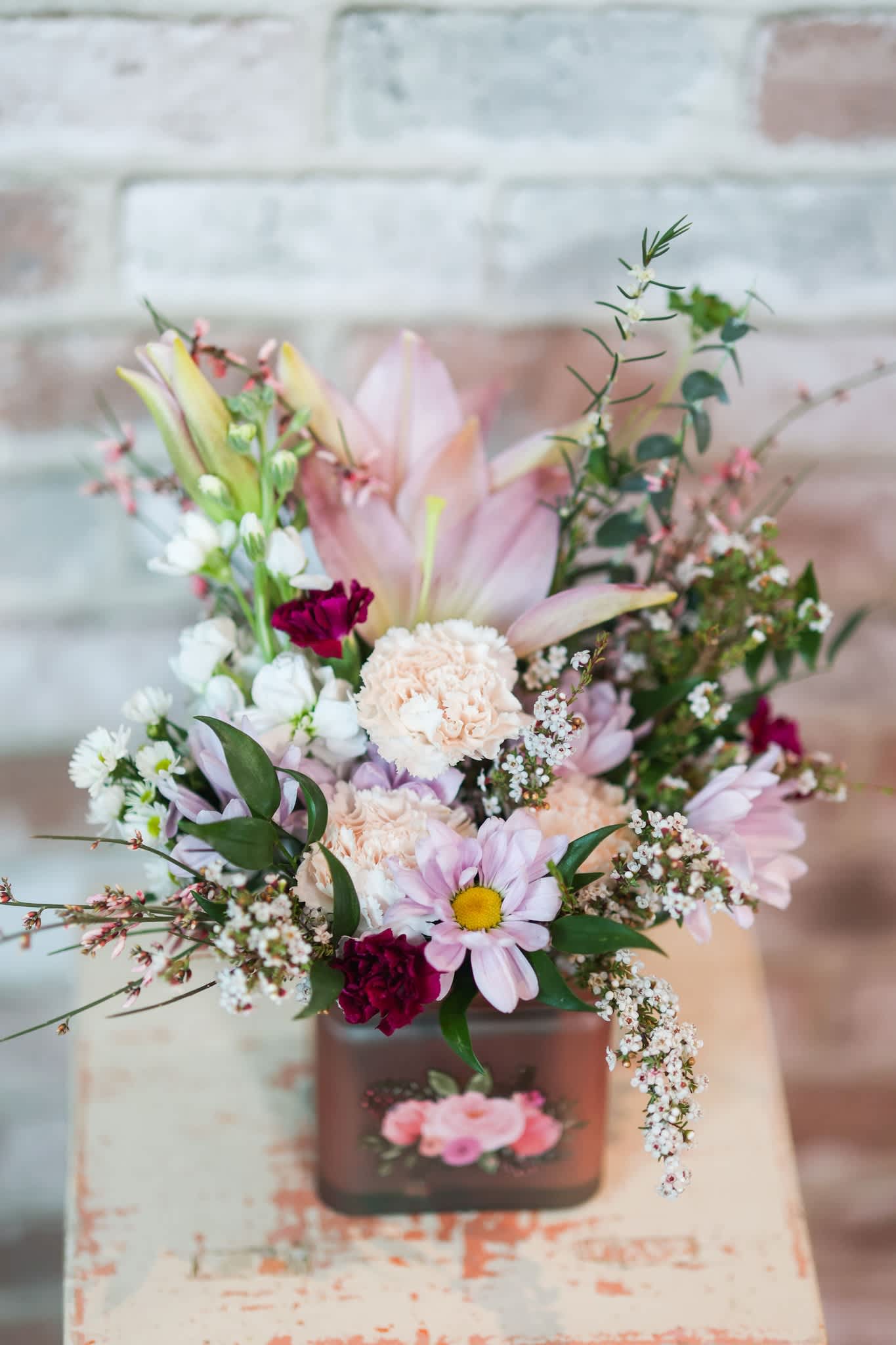 Pastel bouquet in a square vase with lilies, daisies, and carnations