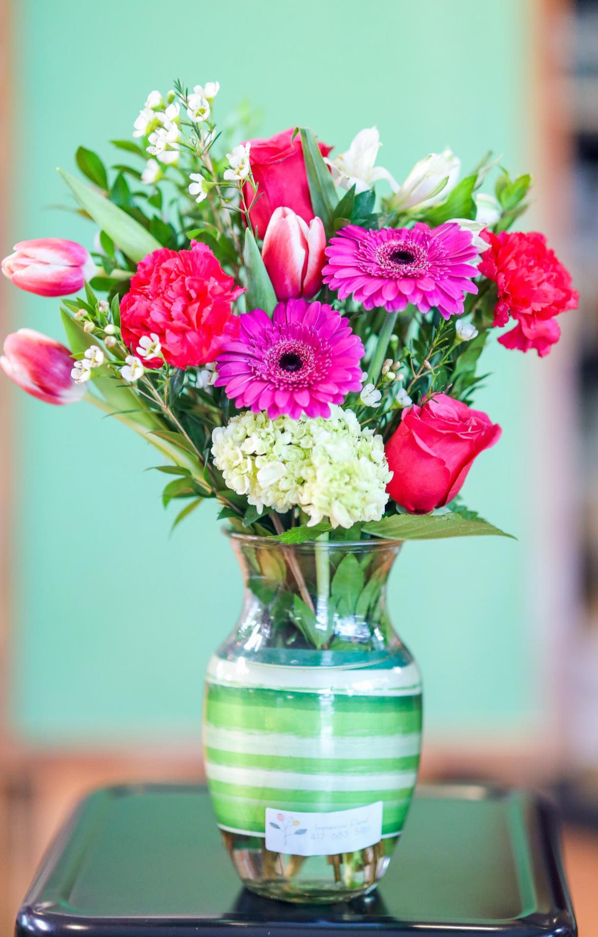 Pink and white mixed bouquet in a striped glass vase