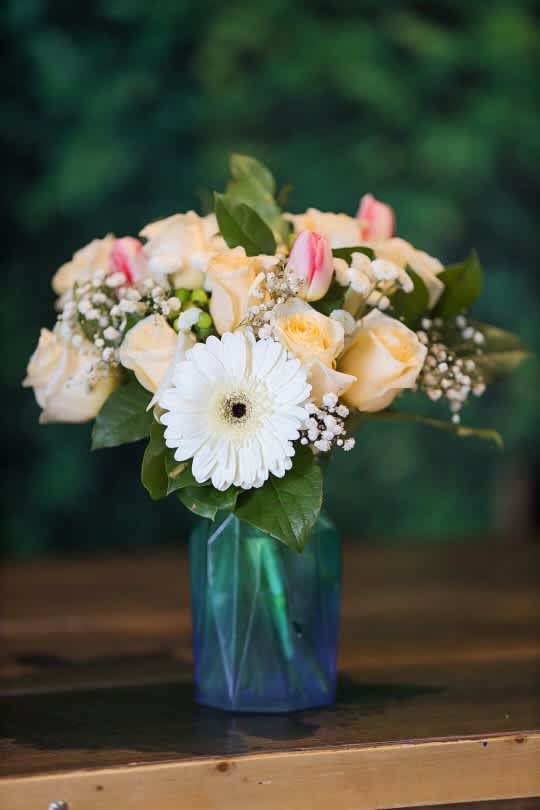 Bouquet of cream roses, pink tulips, and a white gerbera in a blue vase