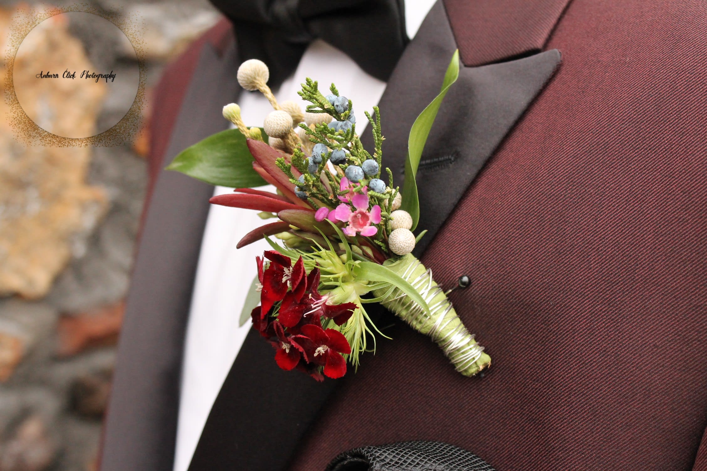 Boutonniere with red flowers and blue berries on a suit lapel
