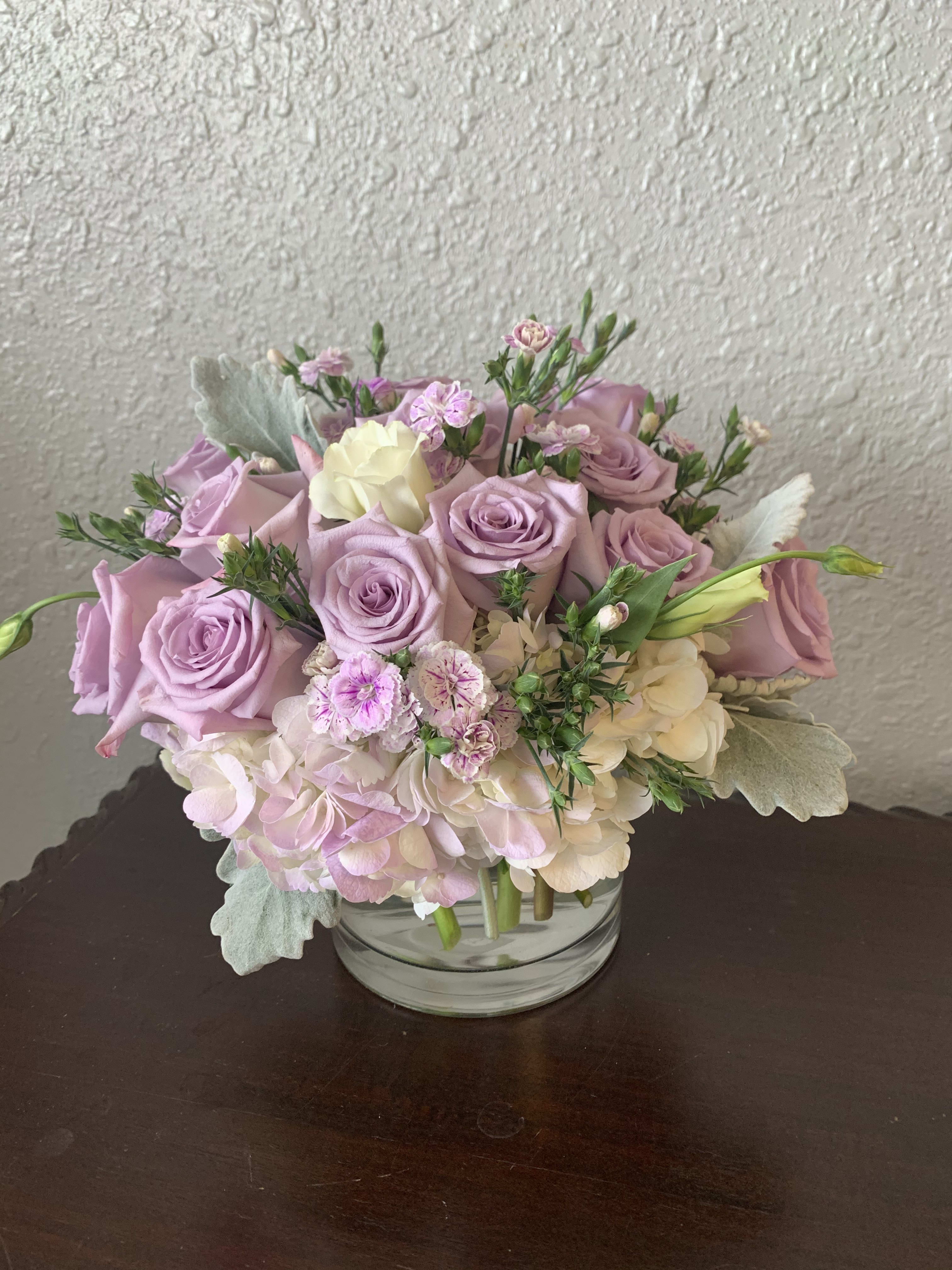 Lavender roses and pale hydrangeas in a clear glass vase