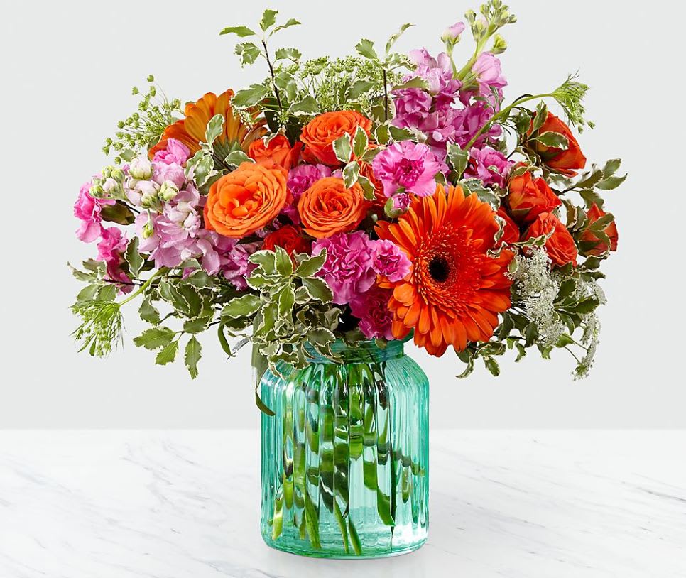 Aqua Escape™ Bouquet by FTD® - VASE INCLUDED - FTD® proudly presents the Aqua Escape™ Bouquet. A bold mix of color your special recipient will never forget, this simply stunning fresh flower bouquet is ready to make that perfect impression. Bringing together brilliant orange gerbera daisies, orange spray roses, fragrant pink gilly flower, and lavender mini carnations, accented with fronds of Queen Anne's Lace and lush greens, this flower arrangement is a memory maker. Presented in an aqua colored glass vase to give it a beachy, summertime feel, this flower bouquet is ready to create a wonderful thank you, thinking of you, or happy birthday gift.