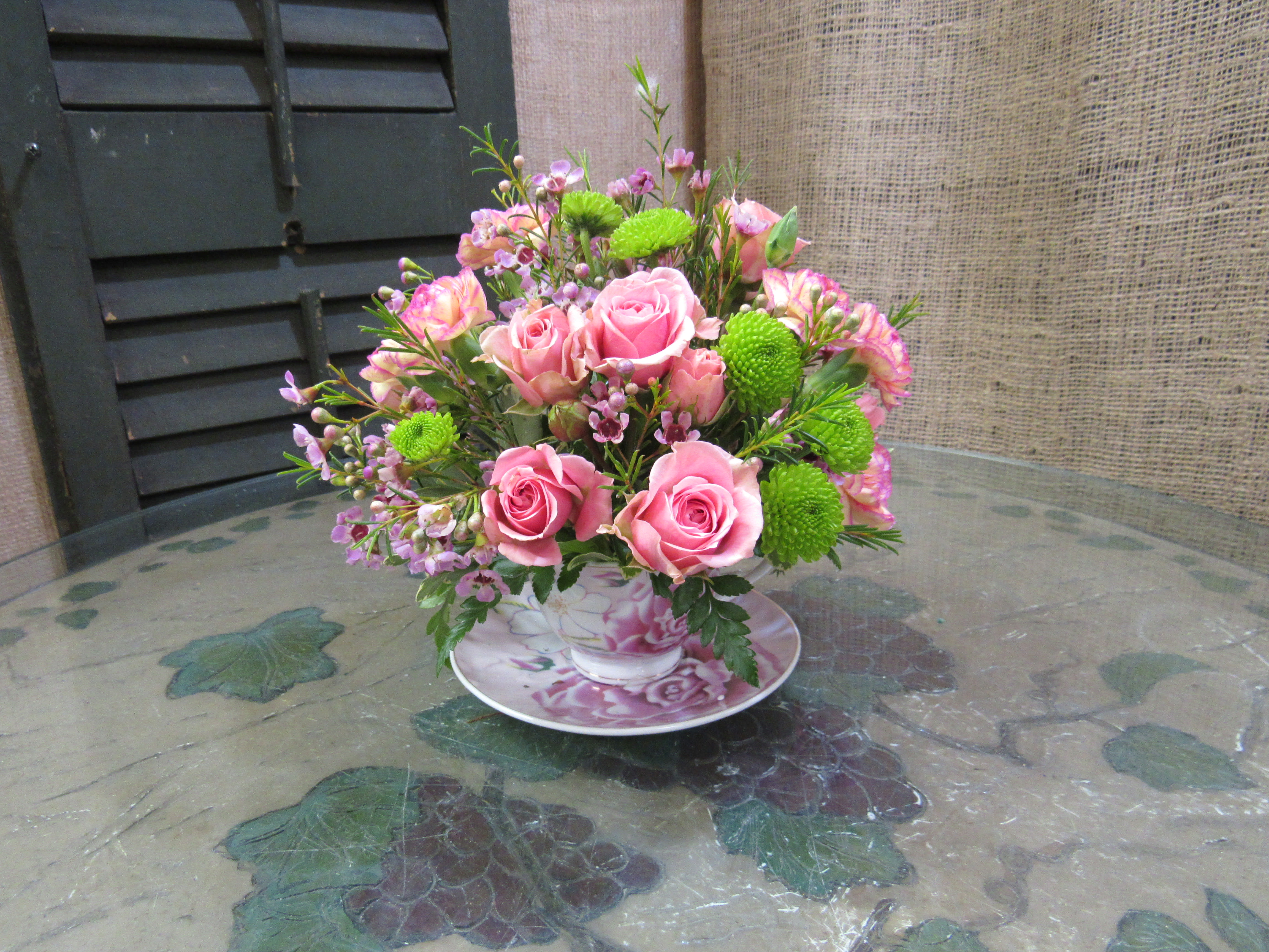Pink rose bouquet in a floral teacup and saucer