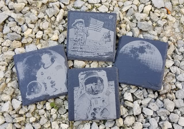Four square slate tiles with astronaut and moon designs on gravel