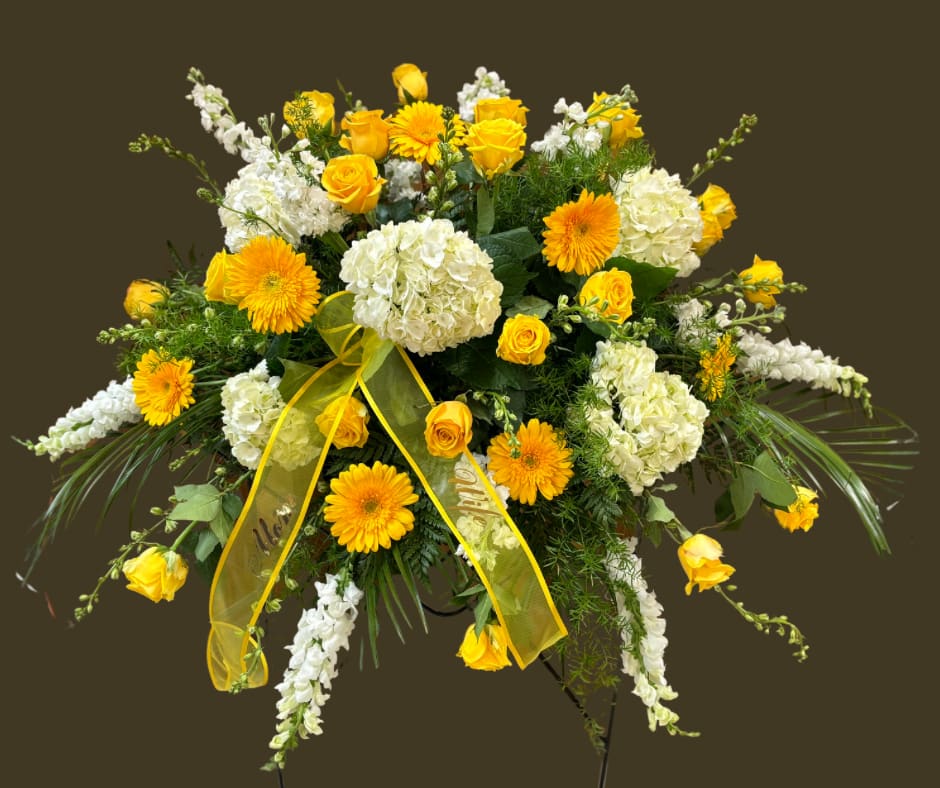 Yellow roses and white hydrangeas in a large standing spray with a yellow ribbon