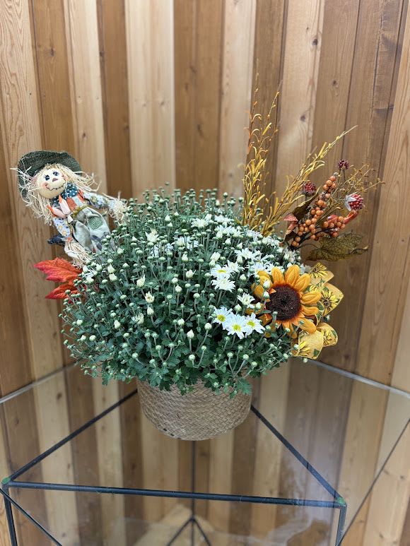 Fall floral arrangement in a woven basket with a scarecrow decoration