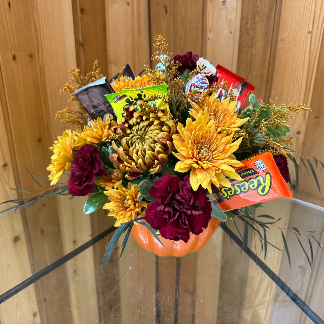 Pumpkin-shaped floral arrangement with yellow and burgundy blooms and candy bars