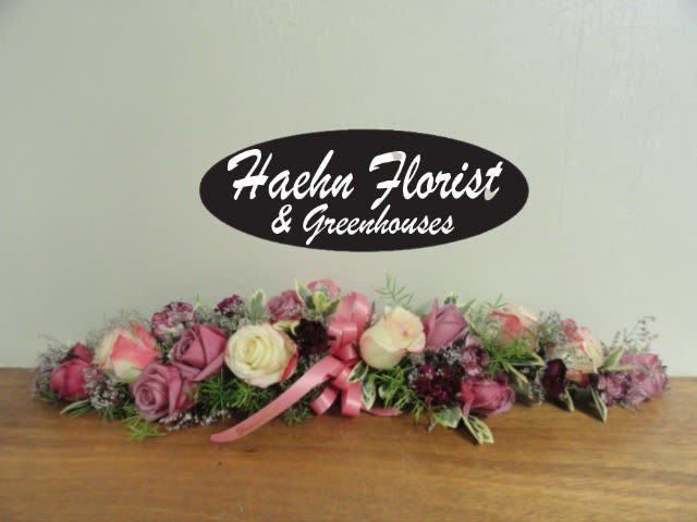 Low floral centerpiece with pink and cream roses and a pink ribbon