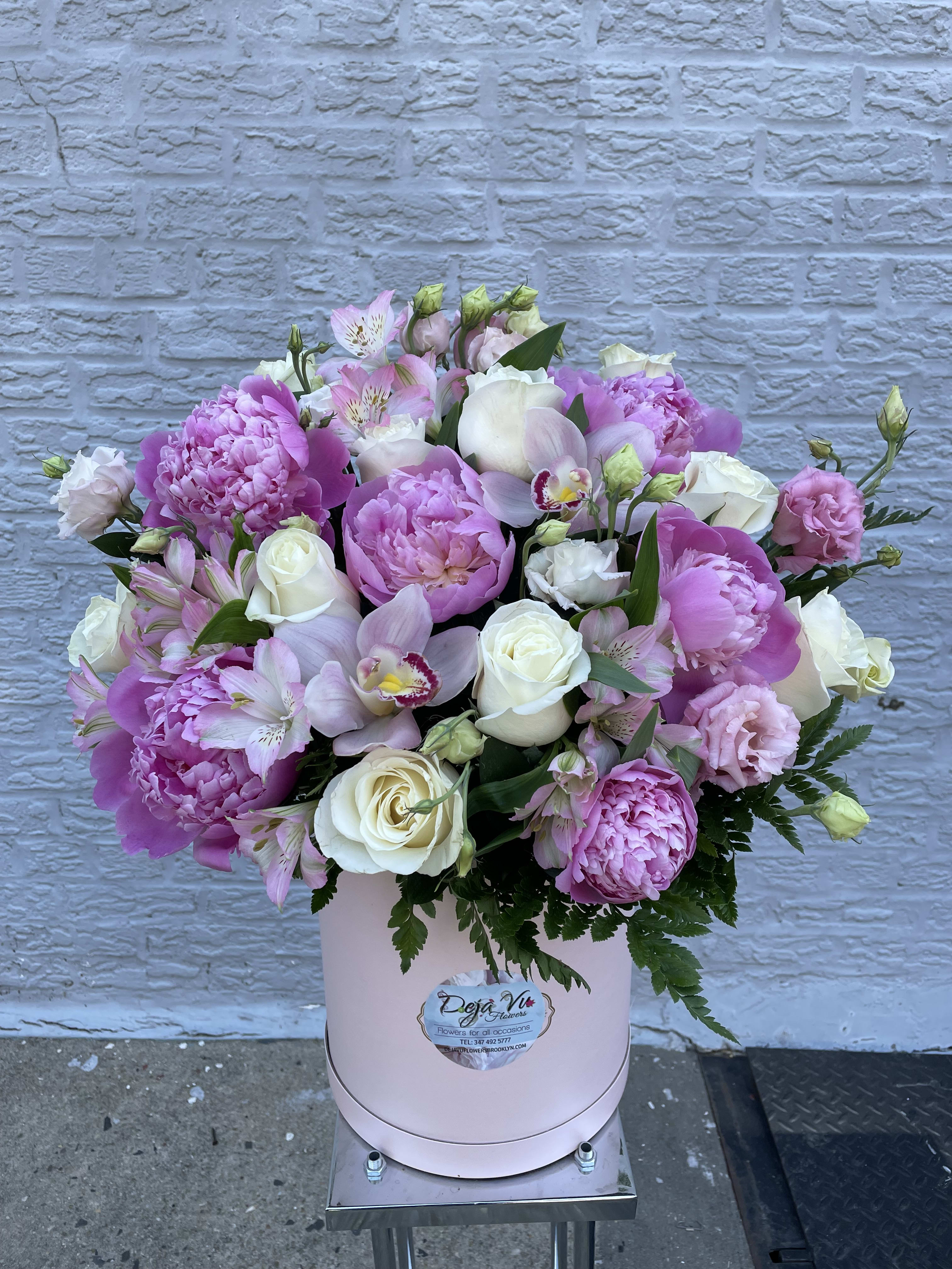 Pink and white mixed flower arrangement in a round box
