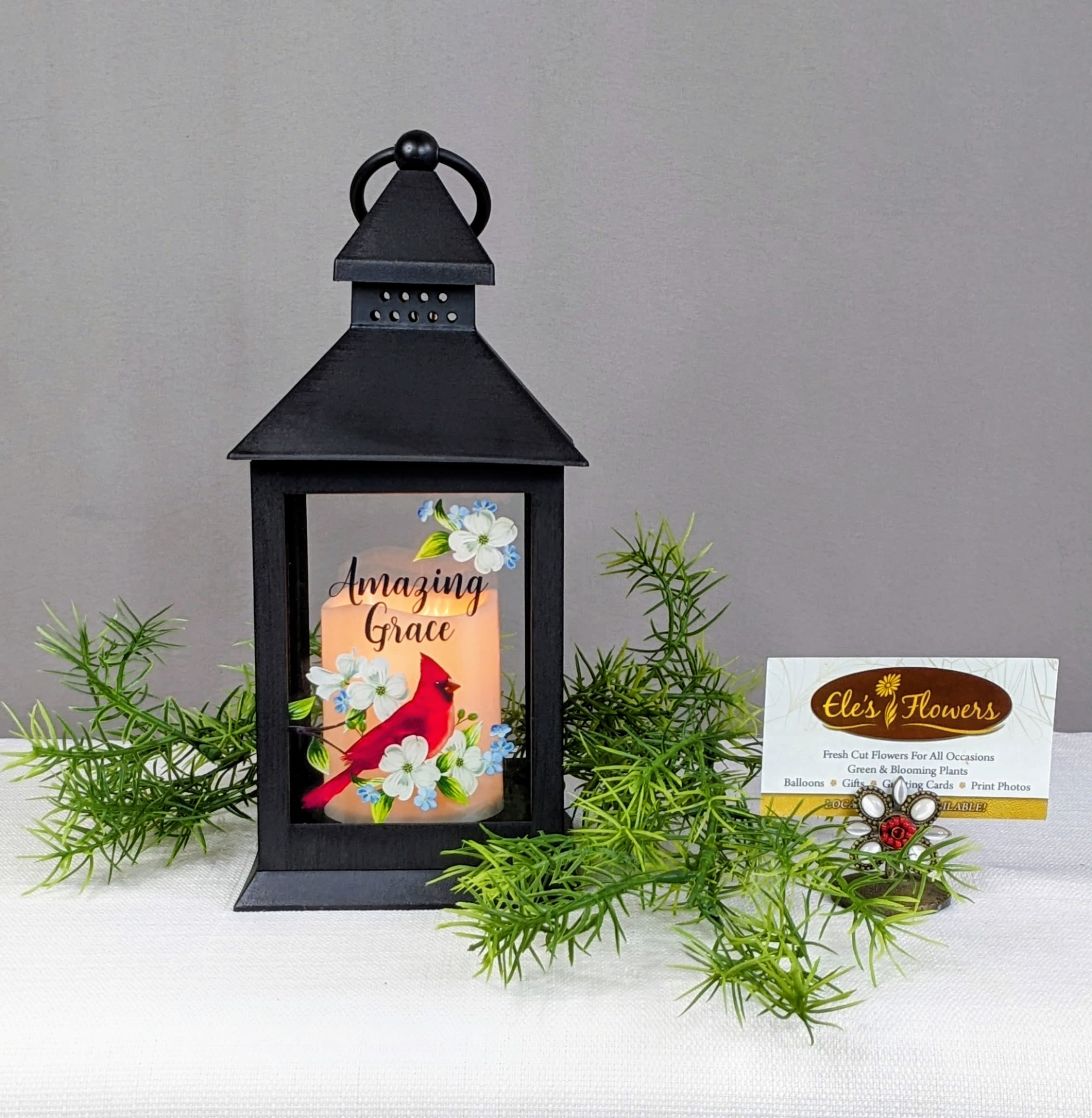 Black lantern with a lit candle and floral cardinal design