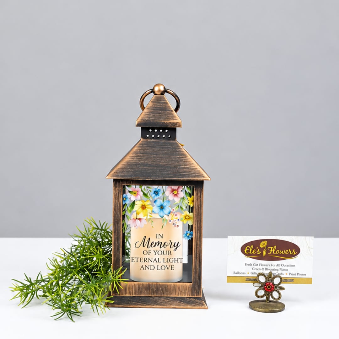 Lantern with memorial candle and floral print, plus a small plant and card