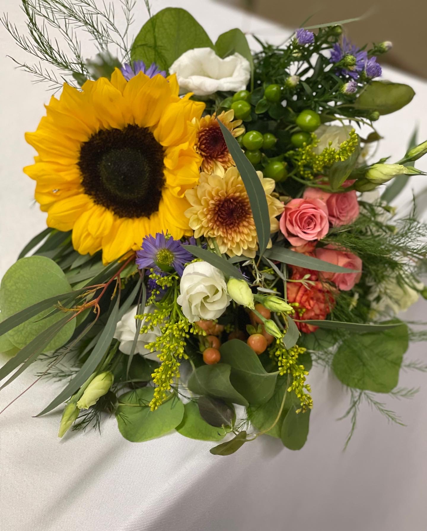 Mixed bouquet with a large sunflower, pink roses, and white blooms