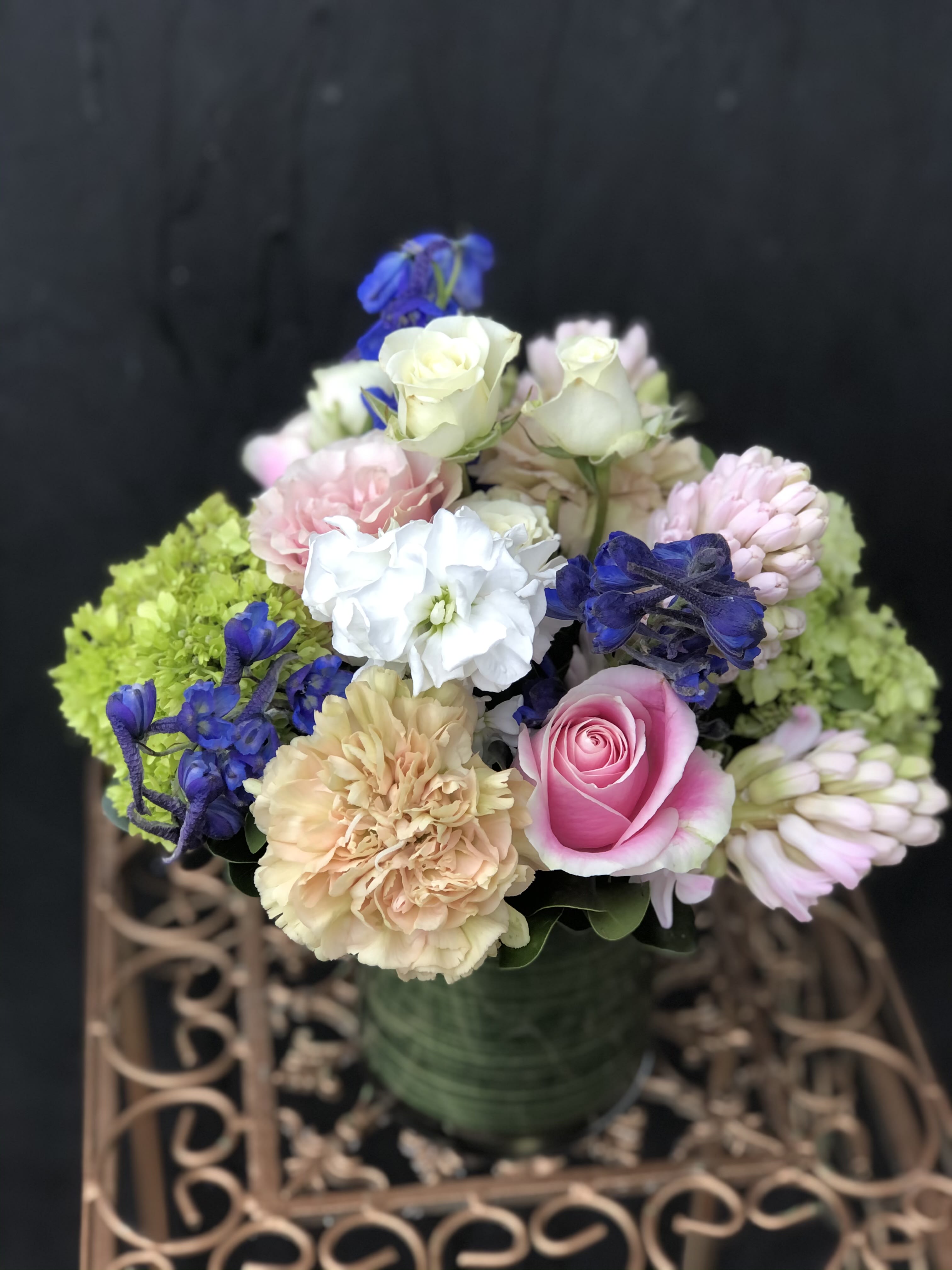 Mixed bouquet of pink, white, and blue flowers in a green vase