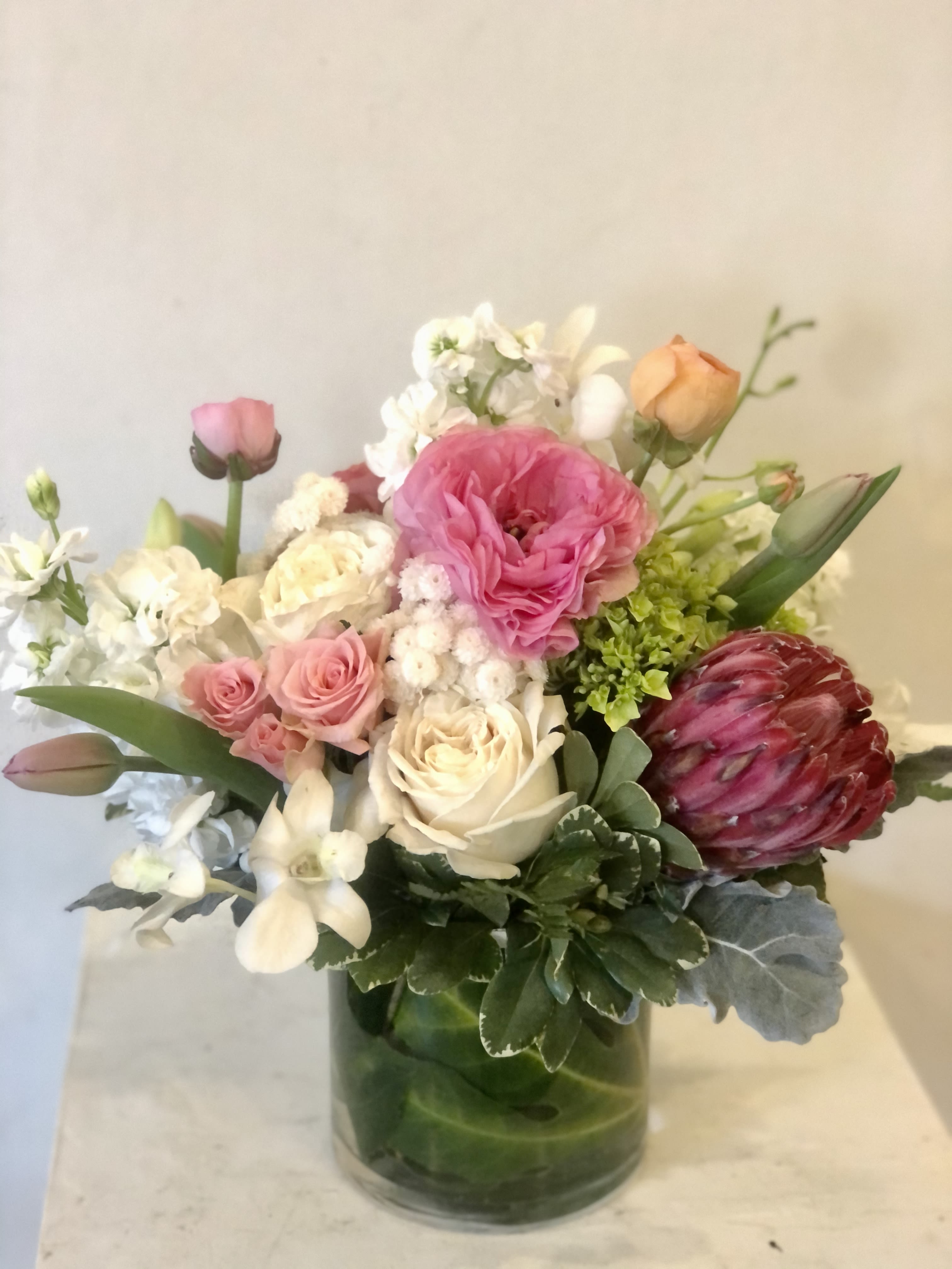 Mixed bouquet of pink, white, and peach flowers in a glass vase