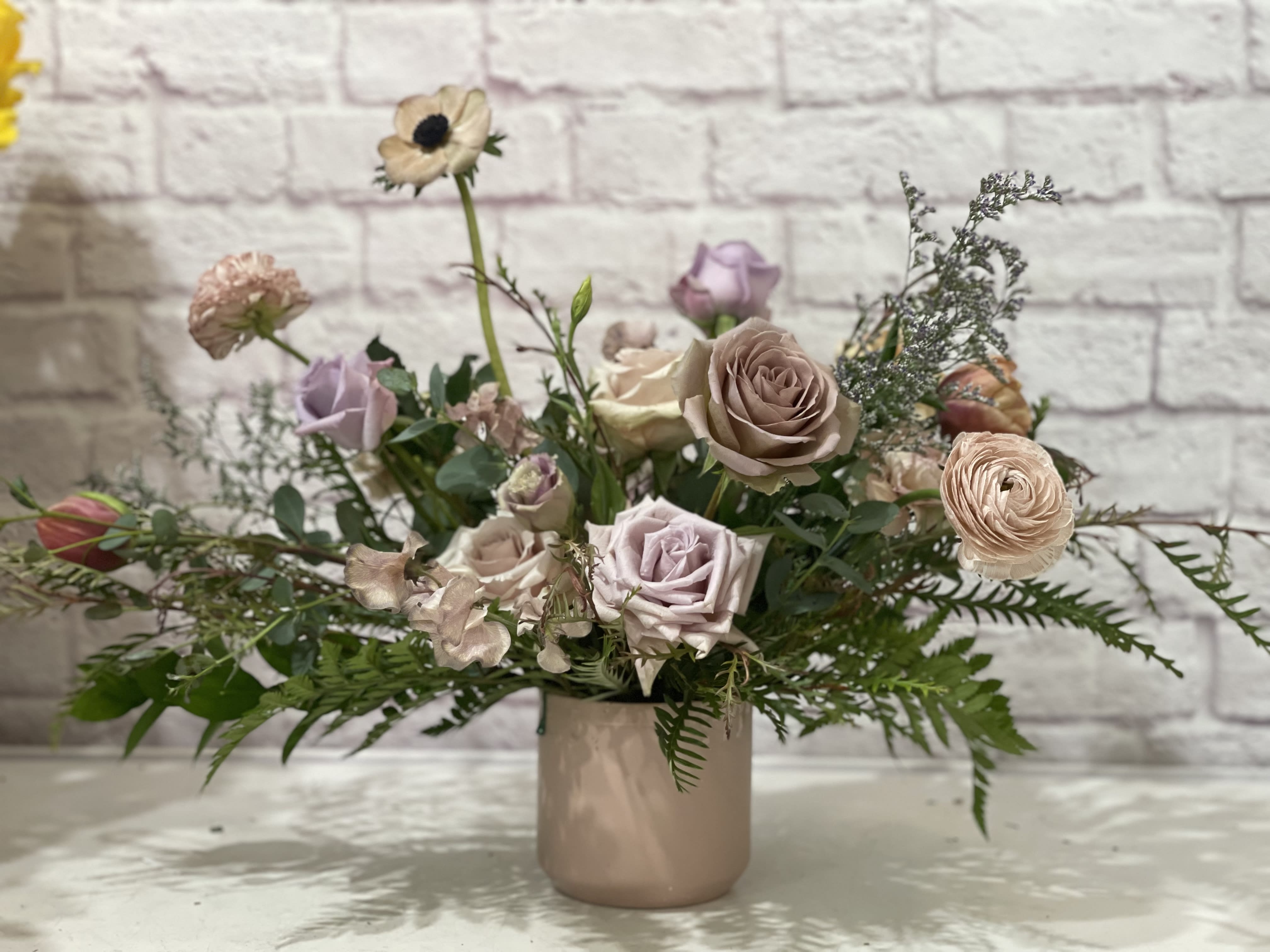 Pastel bouquet of roses and ranunculus in a blush ceramic vase