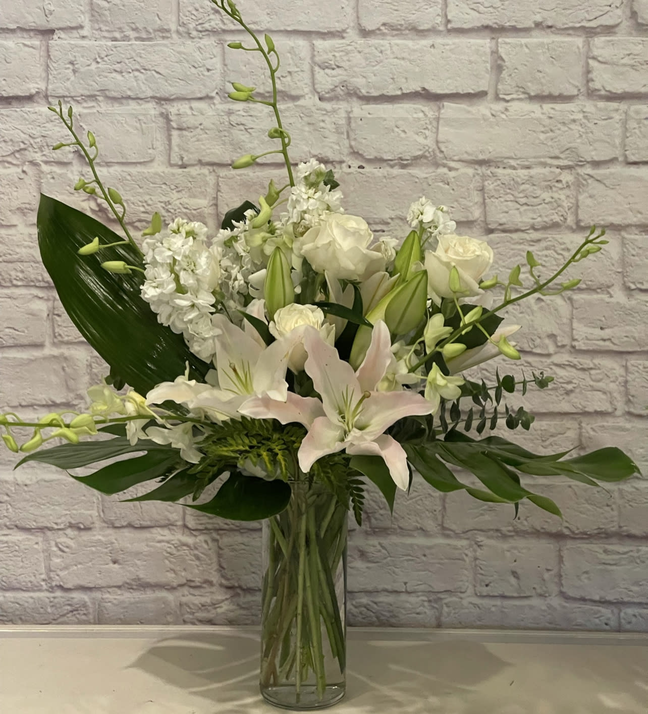 White lilies and roses arranged in a clear glass vase