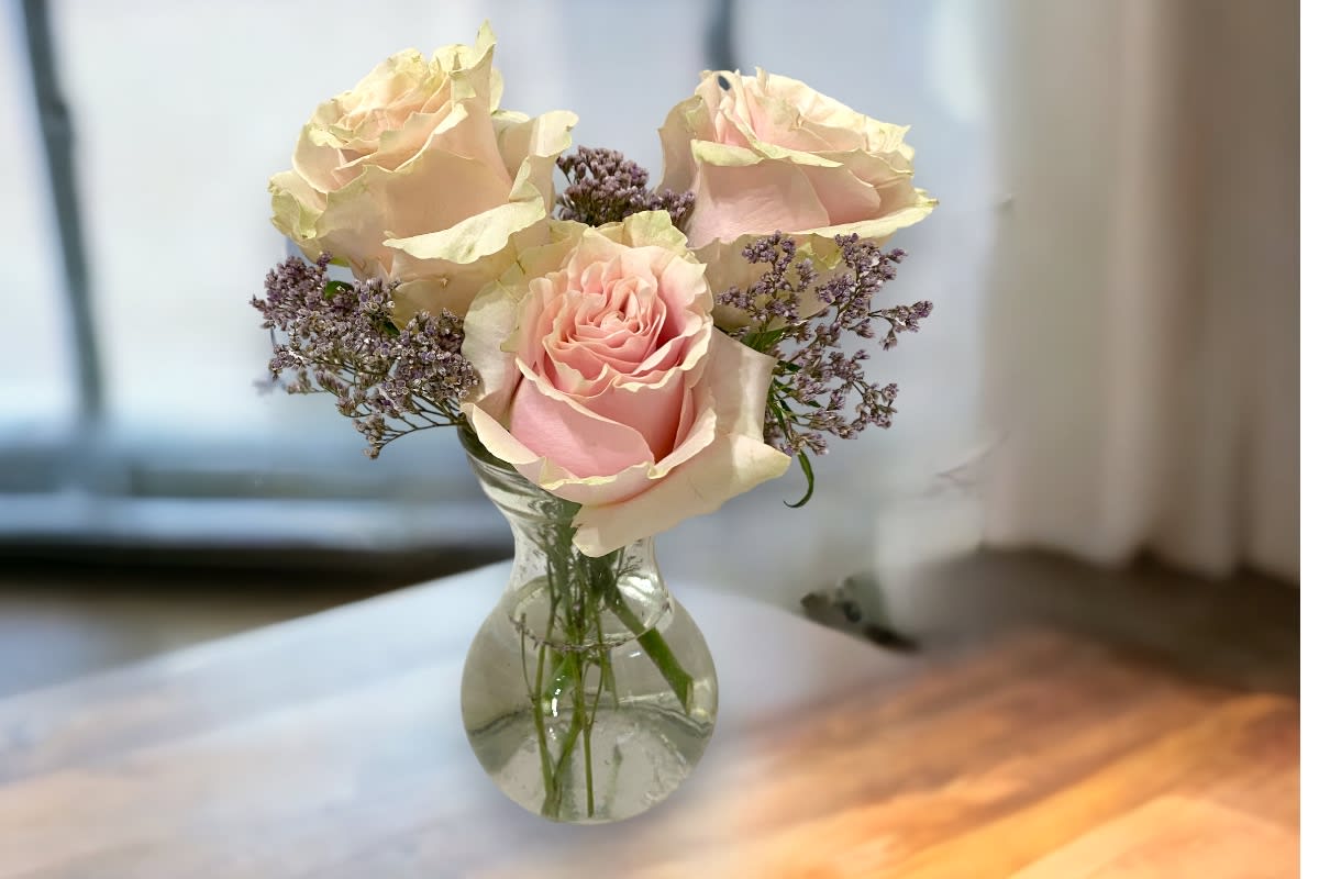 Pink roses and purple filler flowers in a clear glass vase