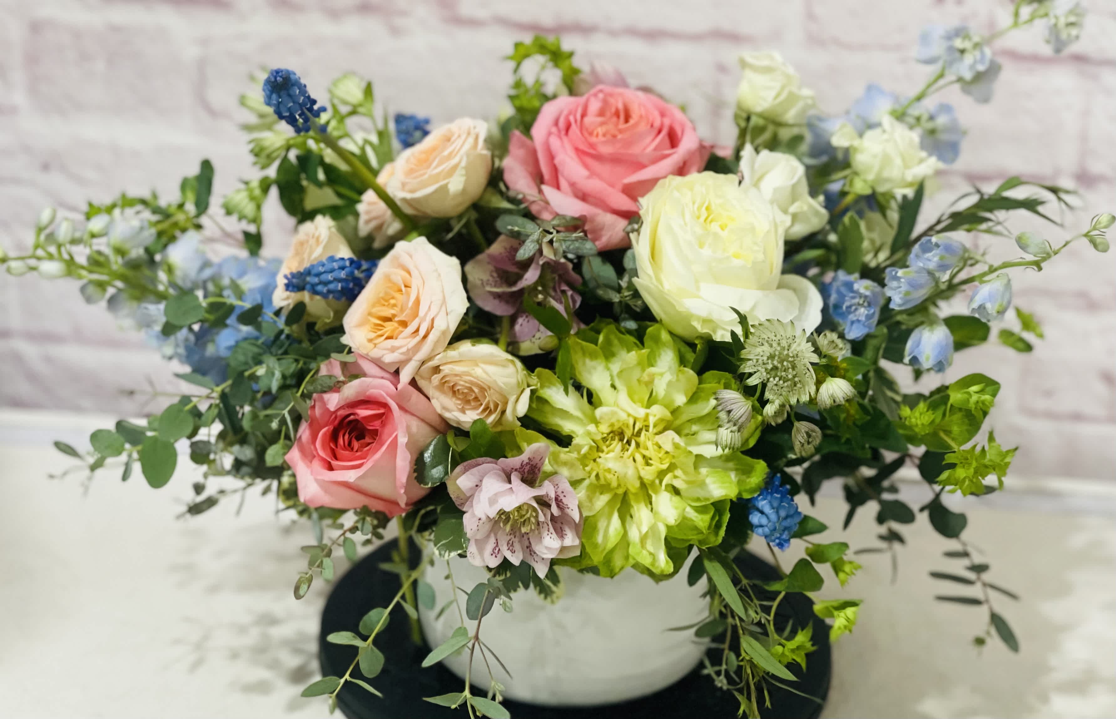 Mixed bouquet of pink, white, and blue flowers in a white vase