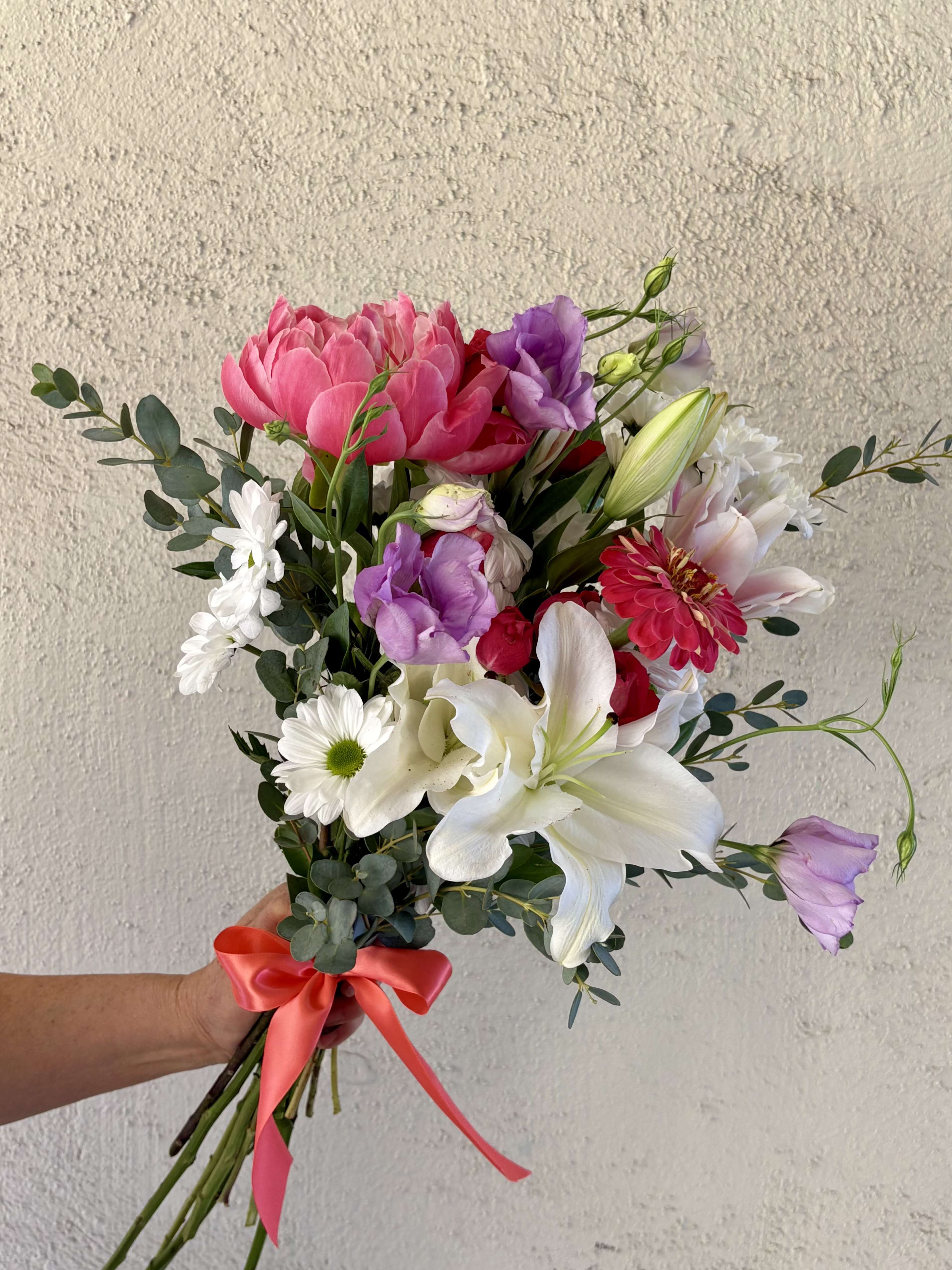 Hand-tied bouquet of pink, white, and purple flowers with a satin ribbon