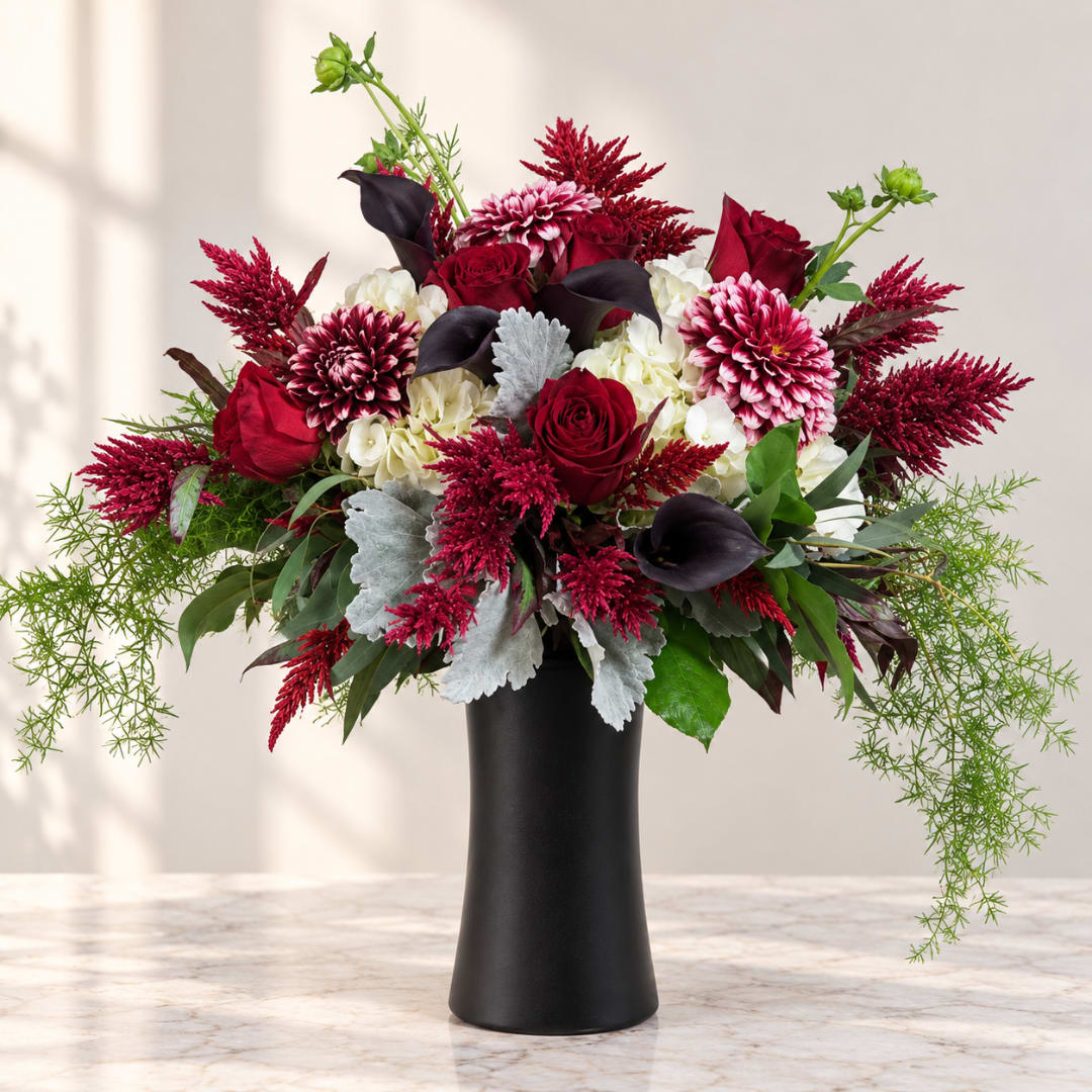 Red and white floral arrangement in a black vase