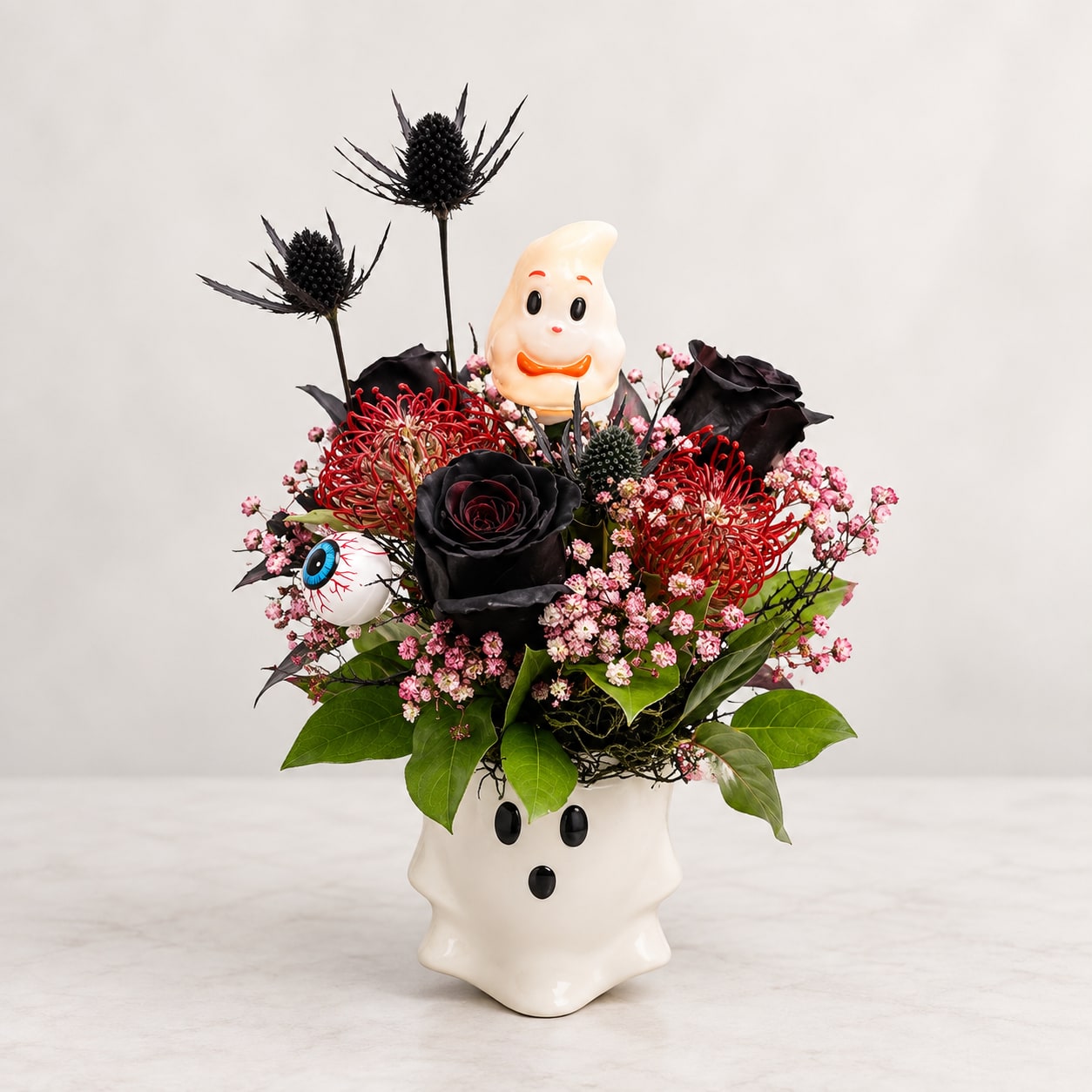 Halloween floral arrangement in a ghost-shaped vase with black and red flowers