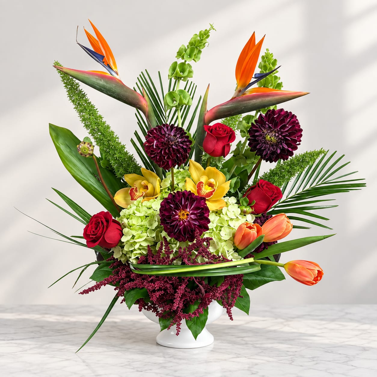 Tropical bouquet with red roses, orchids, tulips, and a white vase
